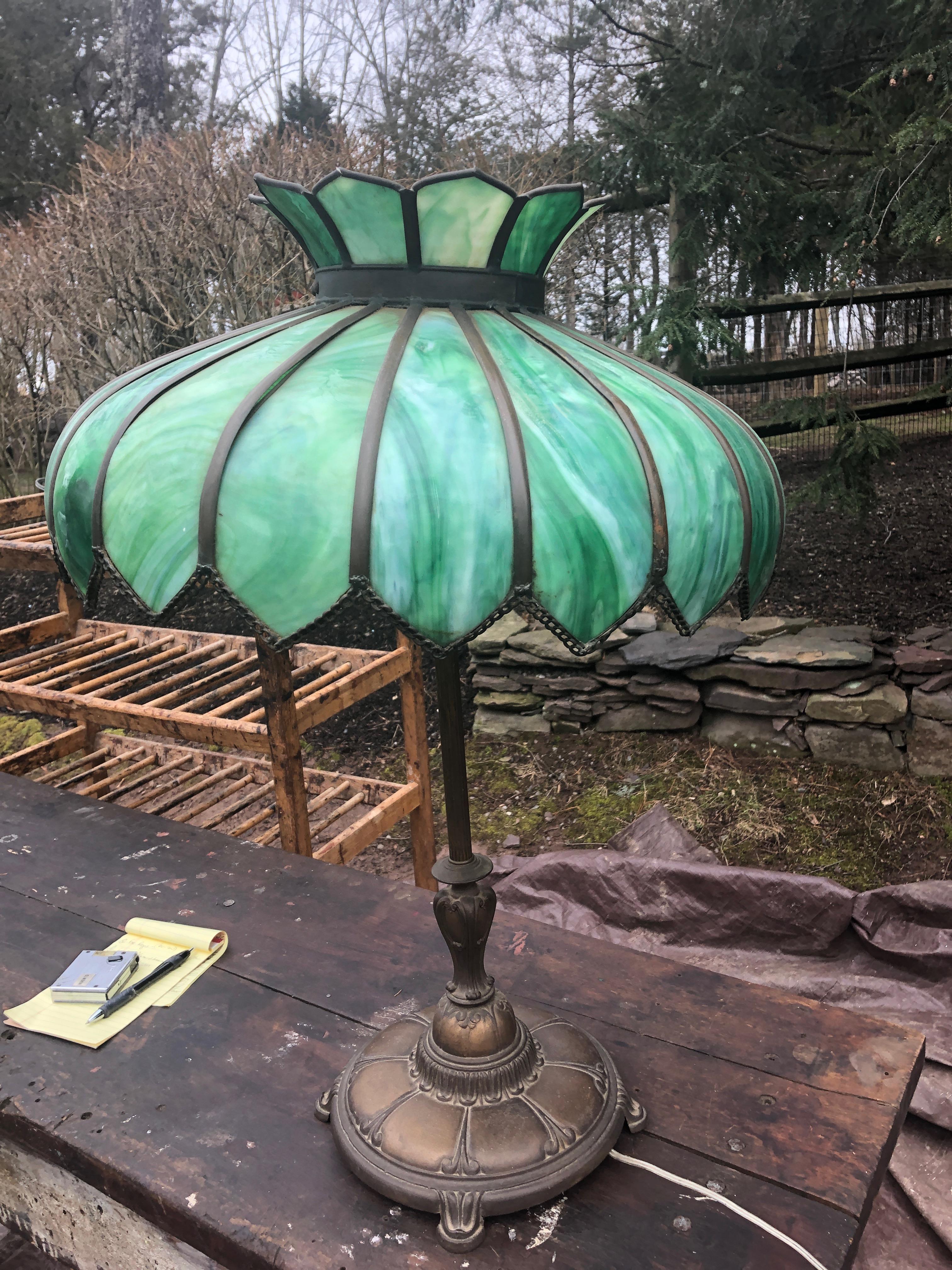 A very large antique leaded glass and brass table lamp having a luminous striking shade in various shades of green. Beautiful both unlit and illuminated.