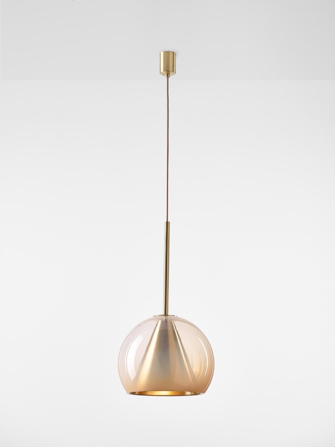 Grande lampe à suspension Kono couleur chair neutre par Dechem Studio
Dimensions : D 35 x H 75 cm
Matériaux : laiton, verre.
Également disponible : différentes finitions et couleurs.

Cette collection de luminaires suspendus associe les formes