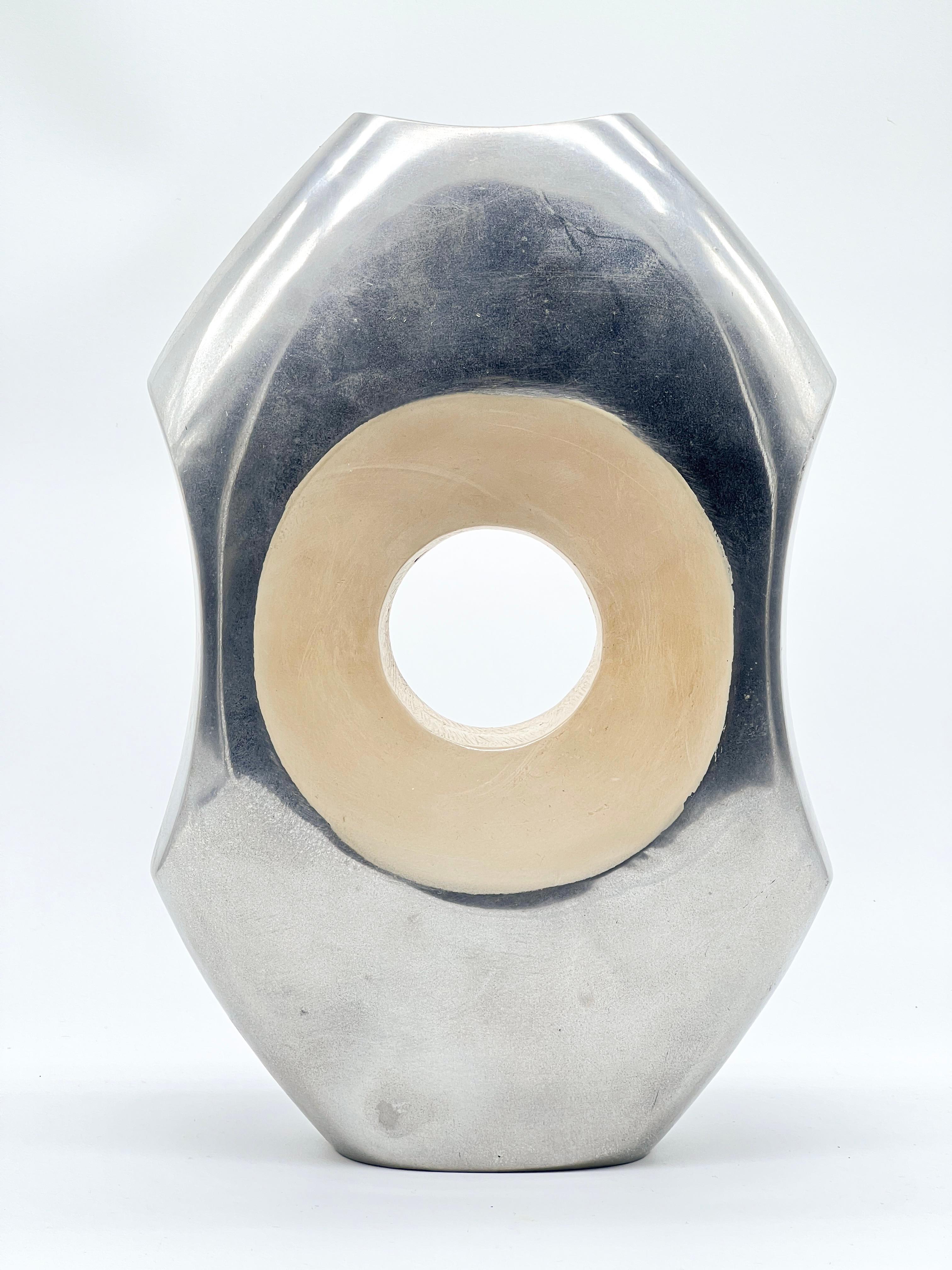 Vintage Space Age vase in cast aluminium, with a hole in the middle and a hand-painted ring on a brushed finish. The carefully refinished surface completely hides the weld joining the two shells, which only remains visible looking inside the vase.