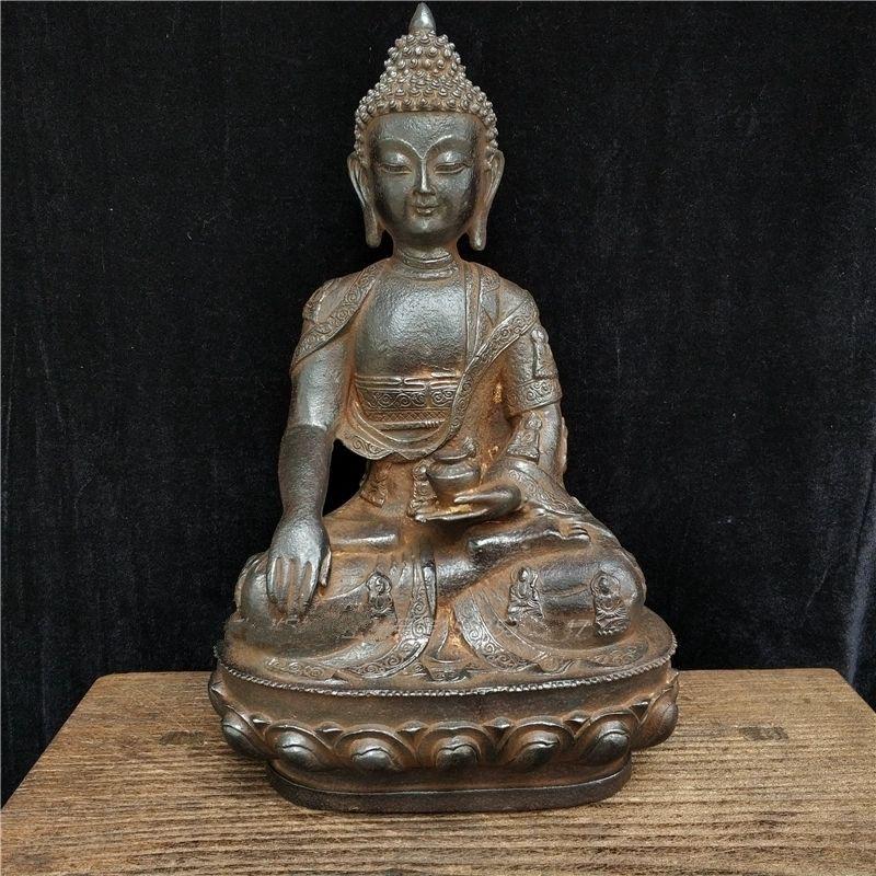 This Big Size Antique Iron Buddha Statue is a remarkable piece of Buddhist art, featuring the Buddha adorned in an intricately detailed garment, known as the Buddha’s robe, covered in fine patterns and symbolic representations. Crafted from solid