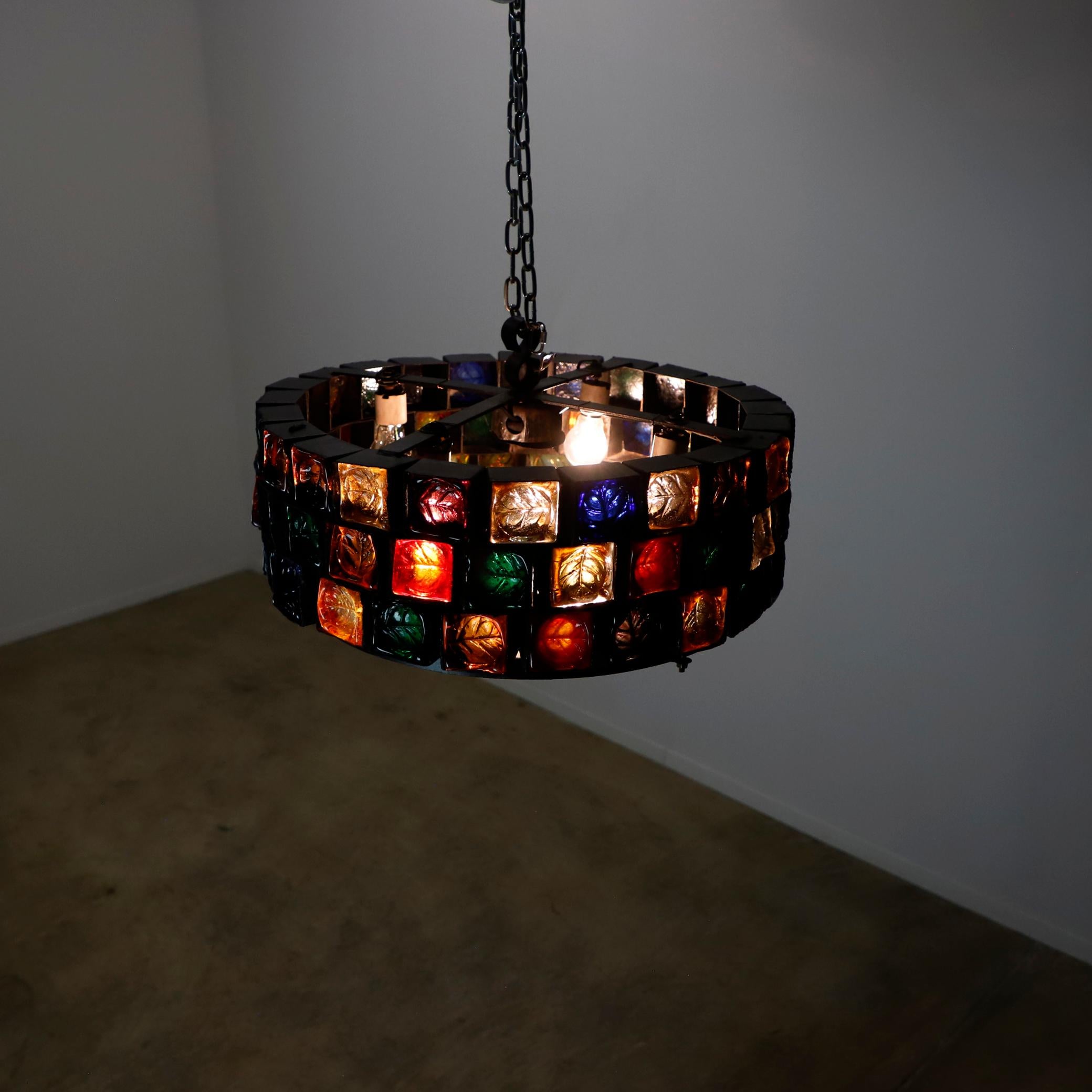 Nous vous proposons ce lustre de grande taille, fait d'acier et de verre soufflé multicolore dans un état vintage fantastique, chaque cube est forgé à la main dans l'acier qui abrite l'épais verre sculpté, le lustre a 69 cubes de verre mesure 6 x 6