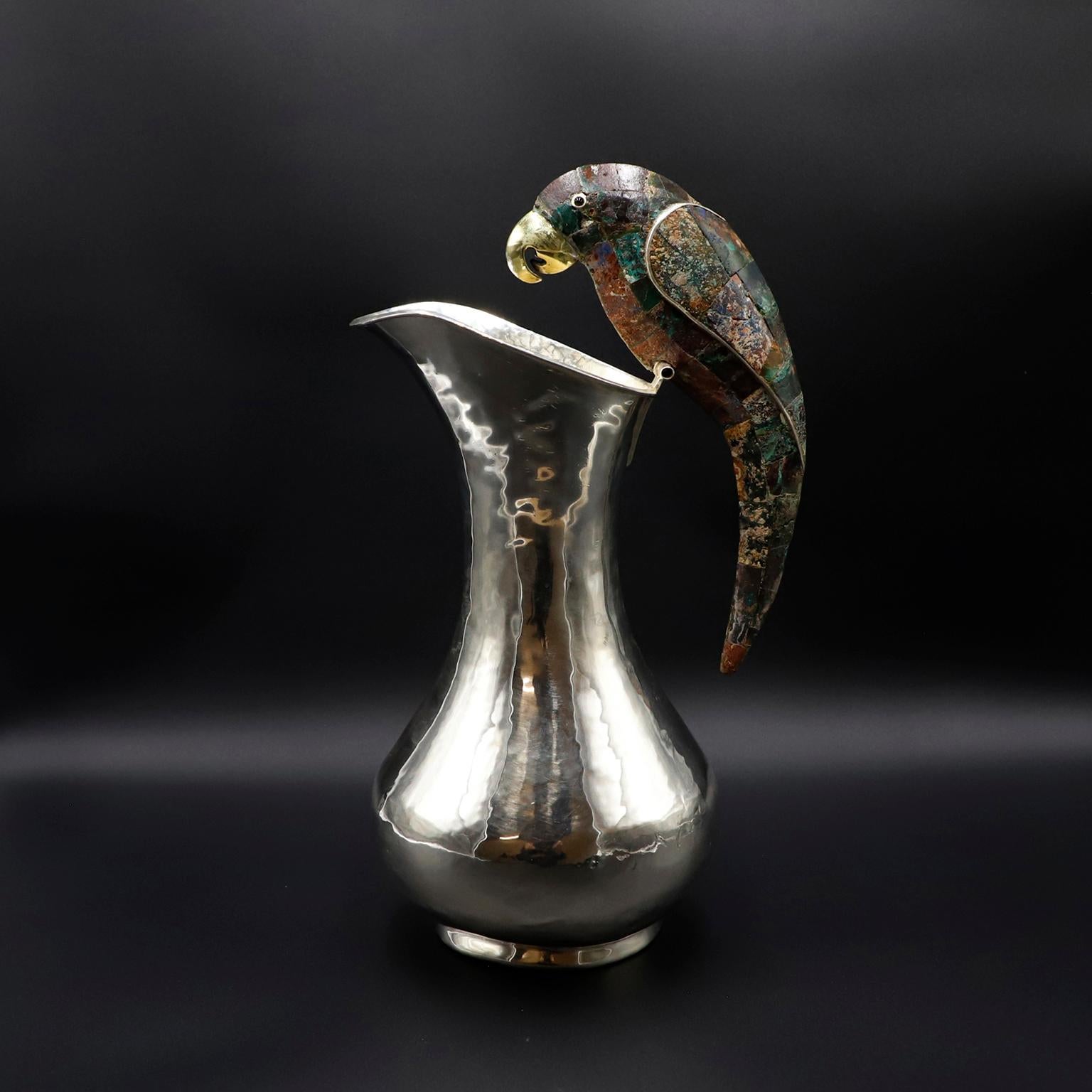 Alrededor de 1960. Te ofrecemos esta jarra mexicana de gran tamaño chapada en plata y malaquita que luce un asombroso asa con motivo de loro, de Los Castillo Taxco México. Se trata de un exquisito y monumental cántaro con el sello de Los Castillo y
