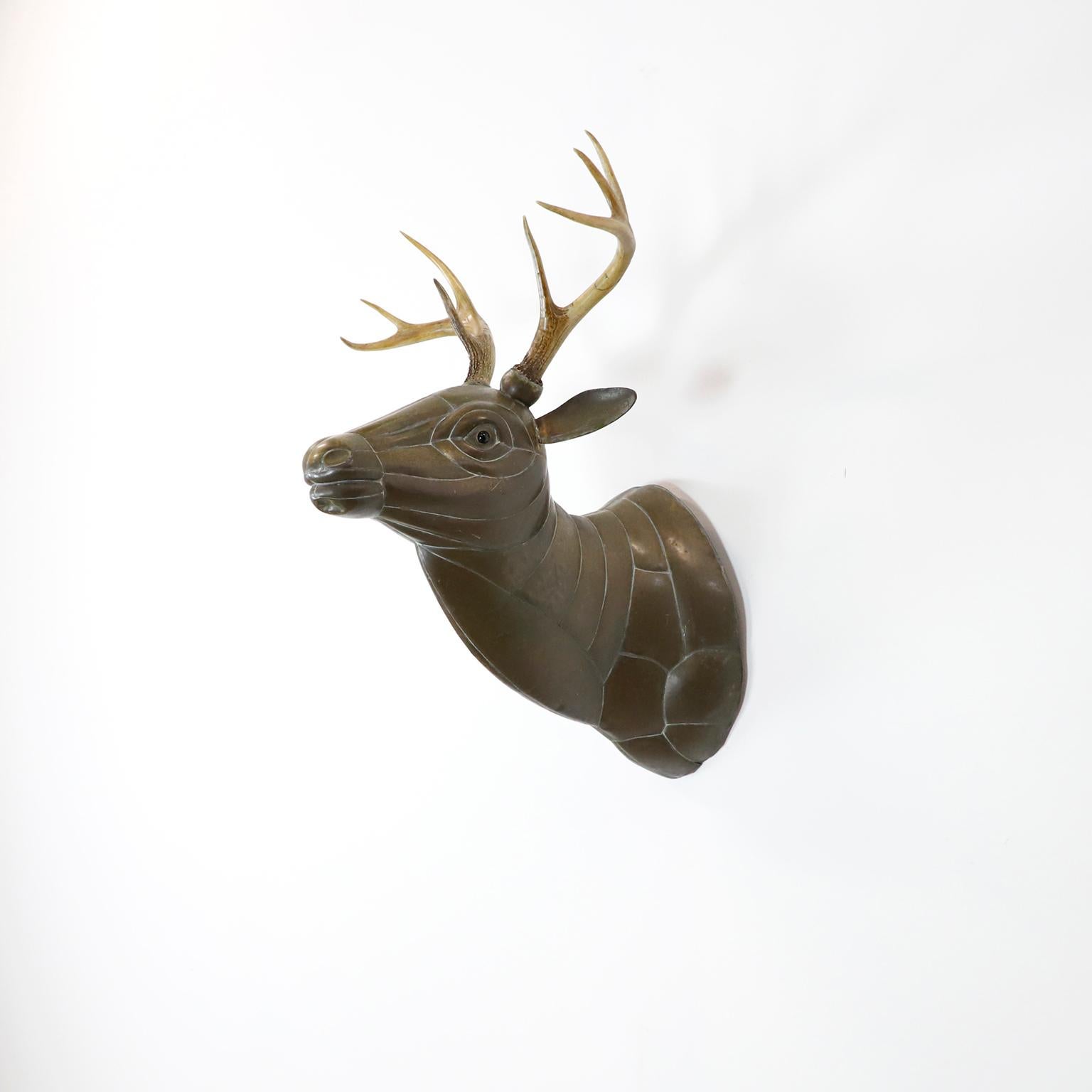 Tête de cerf montée en laiton, découpée, pliée et assemblée, véritables bois, circa 1960.

Sergio Bustamante est un artiste et sculpteur mexicain. Il a commencé par des peintures et des figures en papier mâché, inaugurant la première exposition de