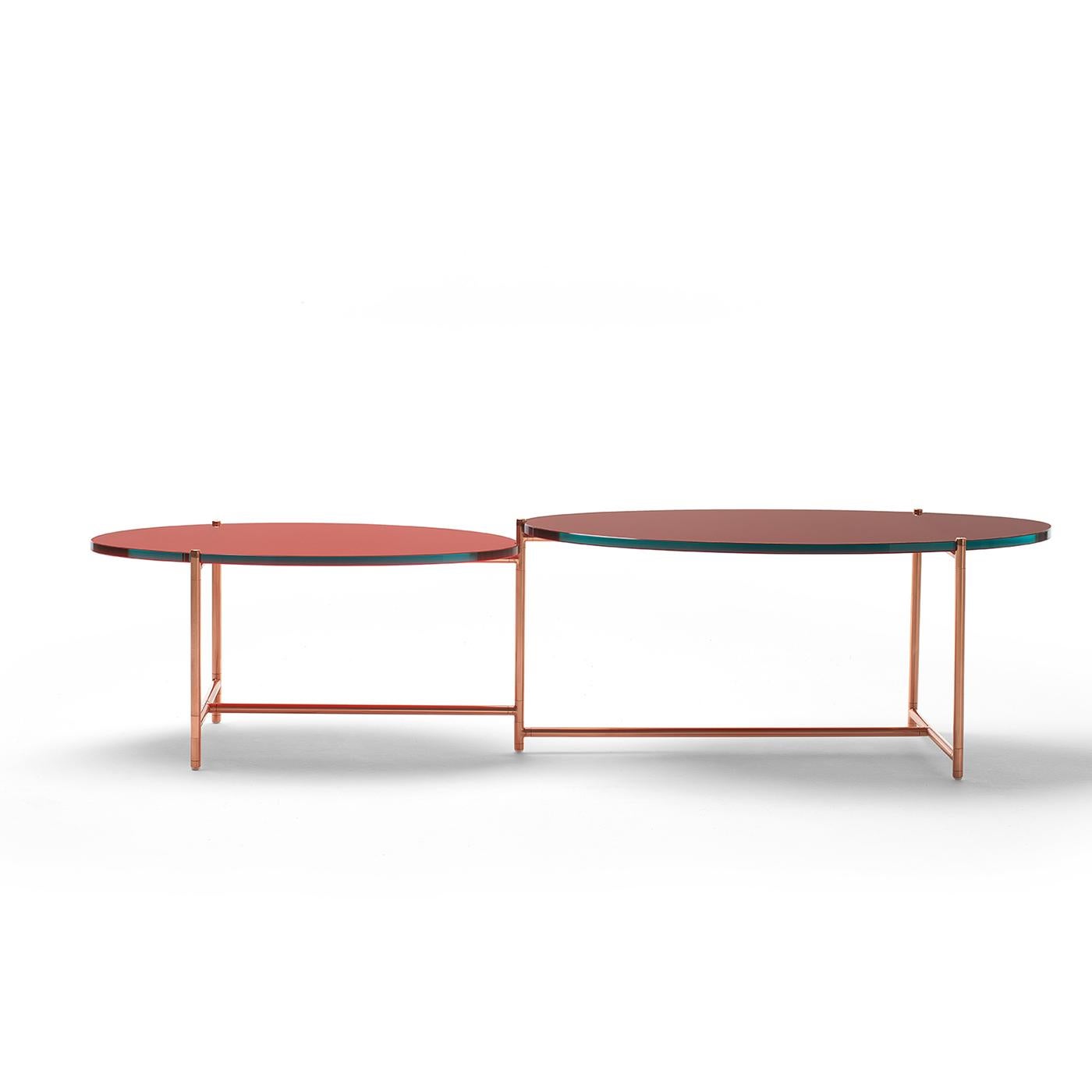 A subtle harmony and balance joins together the components of this cutting-edge coffee table, whose distinctive feature is the asymmetrical tabletops moving around a central pivot fitting. Raised on a slender, cylindrical steel frame covered with