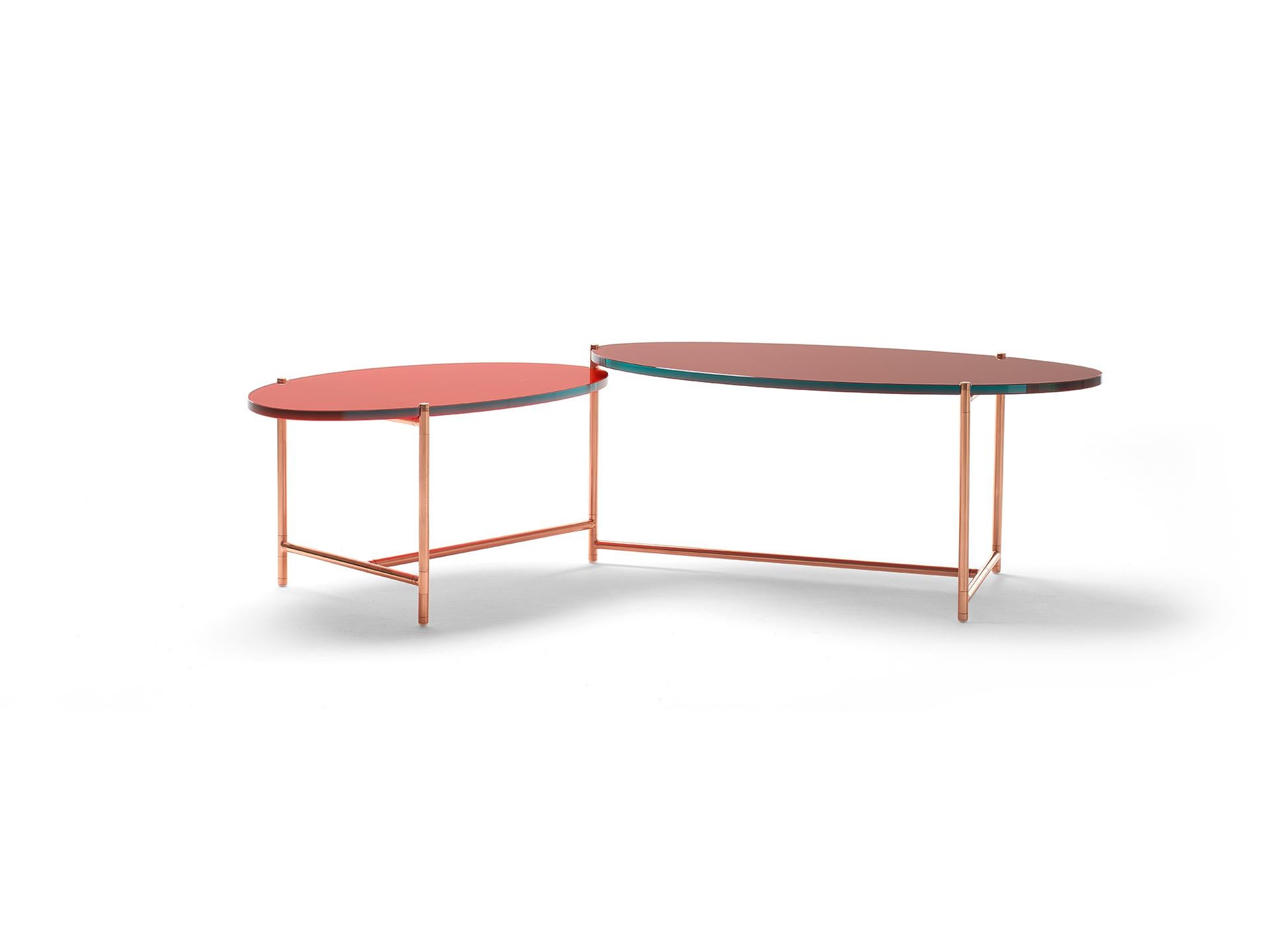 An elegant low table with two tops that can rotate around a central pivoting point, like the hands of a clock. This allows the table to modify its usable surface and to adapt to different uses and spaces. The opposite curves of the two asymmetrical