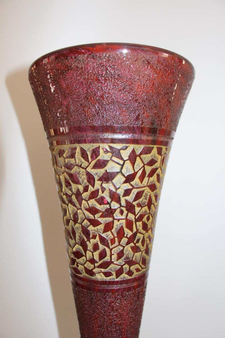 High vase solid double glass tinted red, with flared neck. Decorative stylized leaf friezes engraved in reserve on a background partially frosted with acid on a golden background and jaspered with polychromic interlayer powders. Carries around the
