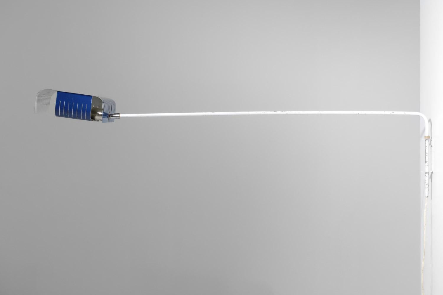 Lange französische Wandlampe aus den 60er / 70er Jahren. Struktur aus weiß lackiertem Metall, Lampenschirm aus perforiertem und gefaltetem Metall, blau und weiß lackiert (Originalfarbe). Möglichkeit der Ausrichtung des Lampenschirms dank eines