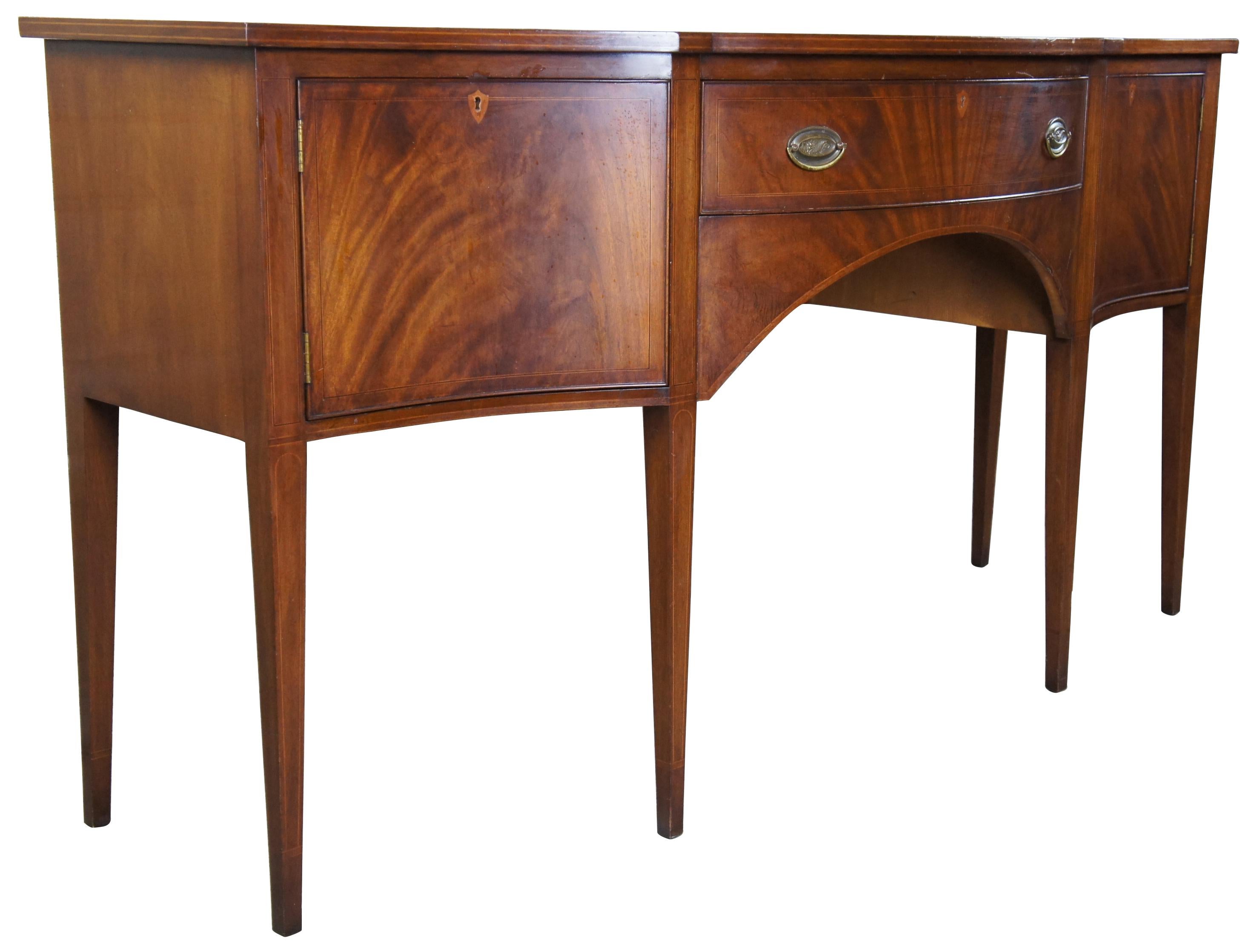 Mid-20th century sideboard by Biggs Furniture Company of Richmond Virginia. Made from flamed mahogany with a contoured bow front over a central drawer and outer cabinets. Features inlay, square tapered legs and brass hardware. Includes a silverware