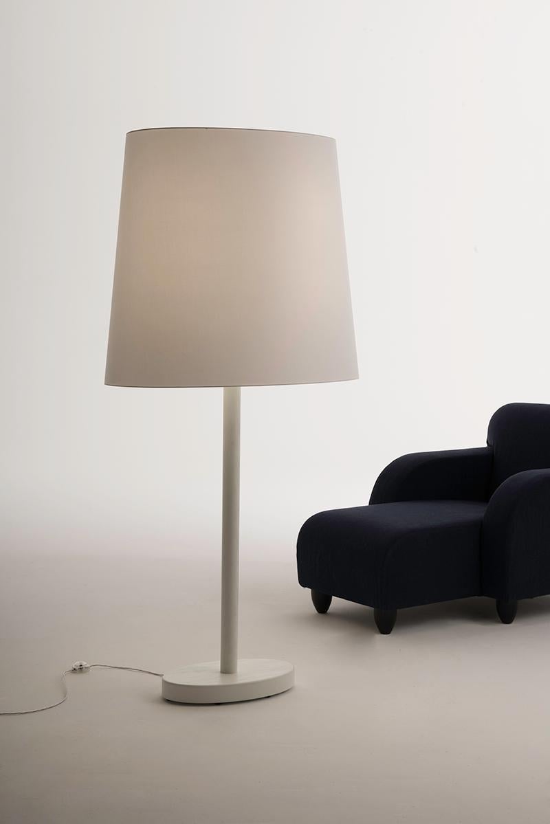 Designed by Aldo Cibic. Big one is an out-of-scale table lamp: a large floor lamp that provides a warm and diffused light. With its structure in white lacquered open-pore ashwood and the large white lampshade in chintz cotton, it fits in the room
