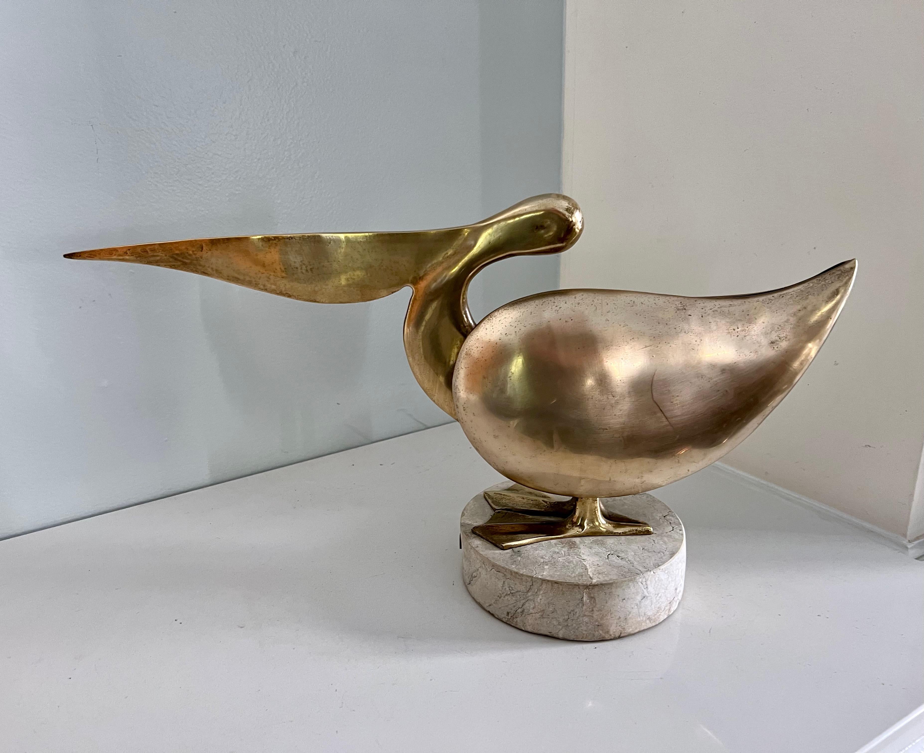 Unique golden brass pelican statue on marble base by artist Bijan. This piece is from the artist's series of 