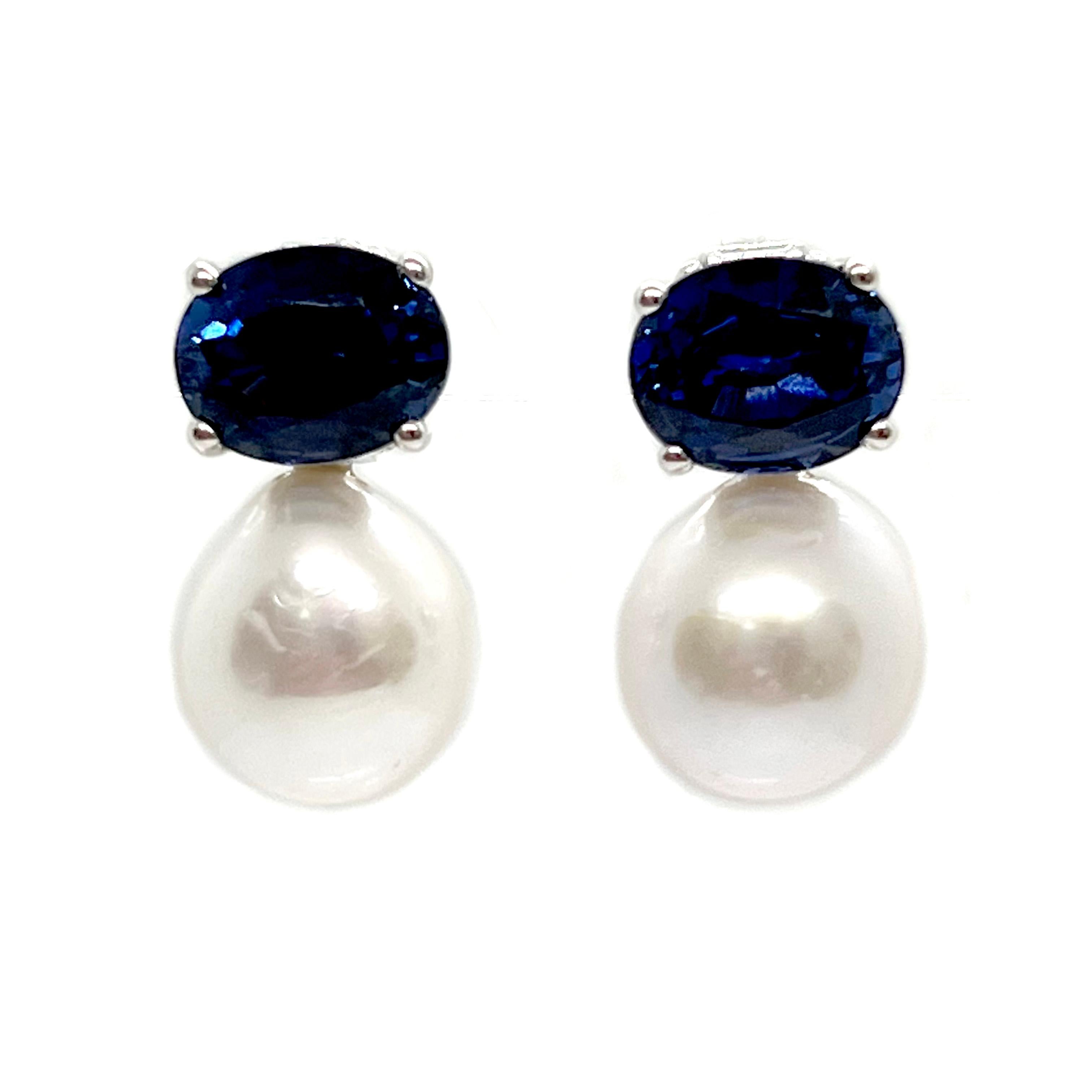 These stunning pair of earrings feature a pair of oval lab-grown blue sapphire (3.5ctw each) and lustrous white cultured freshwater pearls, handset in platinum rhodium plated over sterling silver. The pearls measure 13mm width and 19=4mm height