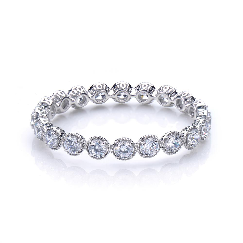 Ce magnifique bracelet présente une rangée de 20 diamants ronds simulés (chaque pierre est d'une taille de 1 carat) avec un motif de halo Perle, sertis dans de l'argent sterling plaqué platine rhodié. Fermeture par fermoir à poussoir avec double