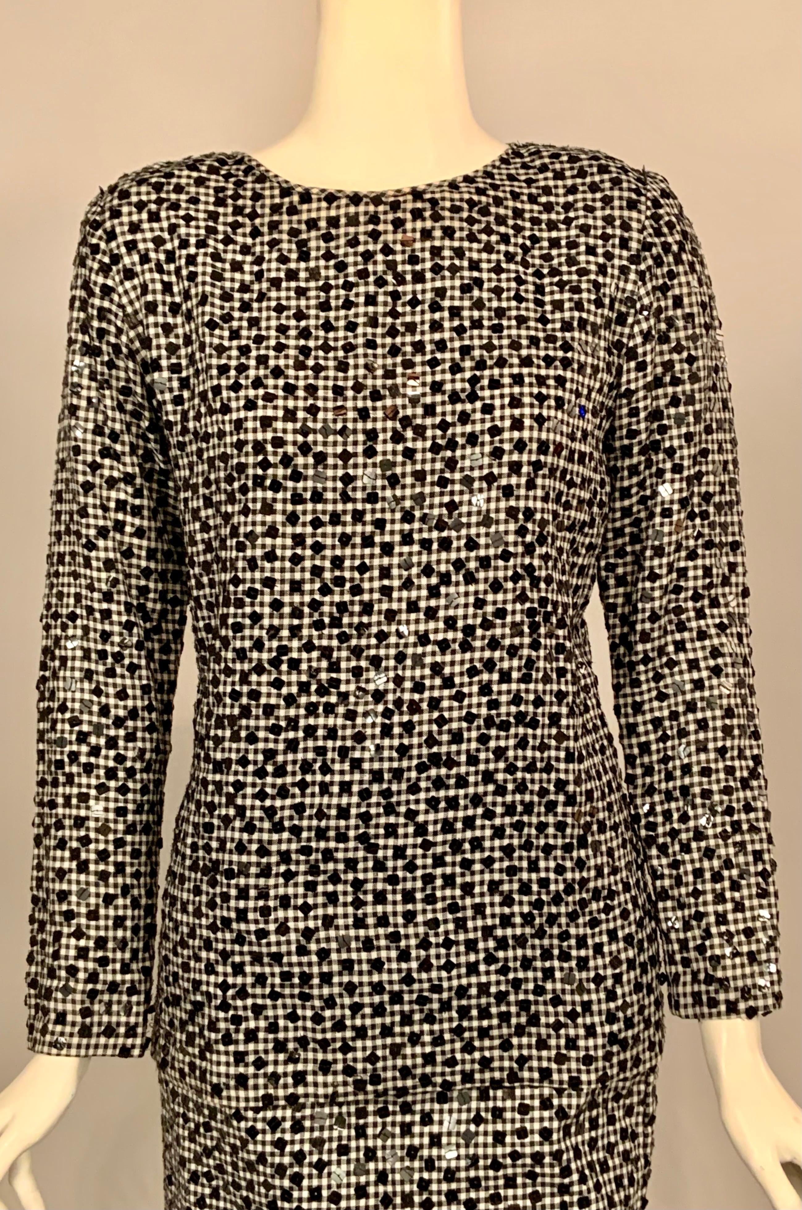 Bill Blass used the unusual combination of black and white gingham and square black sequins to create this two piece dress that takes you from drinks to dinner in style.   The top has a round neckline, long sleeves, buttons at the wrists and an