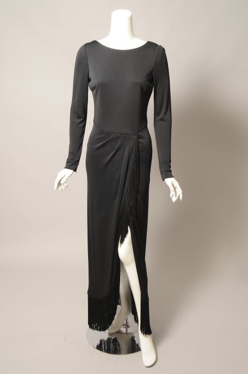 Sleek and elegant, this black silk crepe dress from Bill Blass is a little bit sexy too! The fringe trimmed skirt is slit right up to the waistline. The dress has a scoop neckline that is deeper in the back, long sleeves with zippers at the wrists