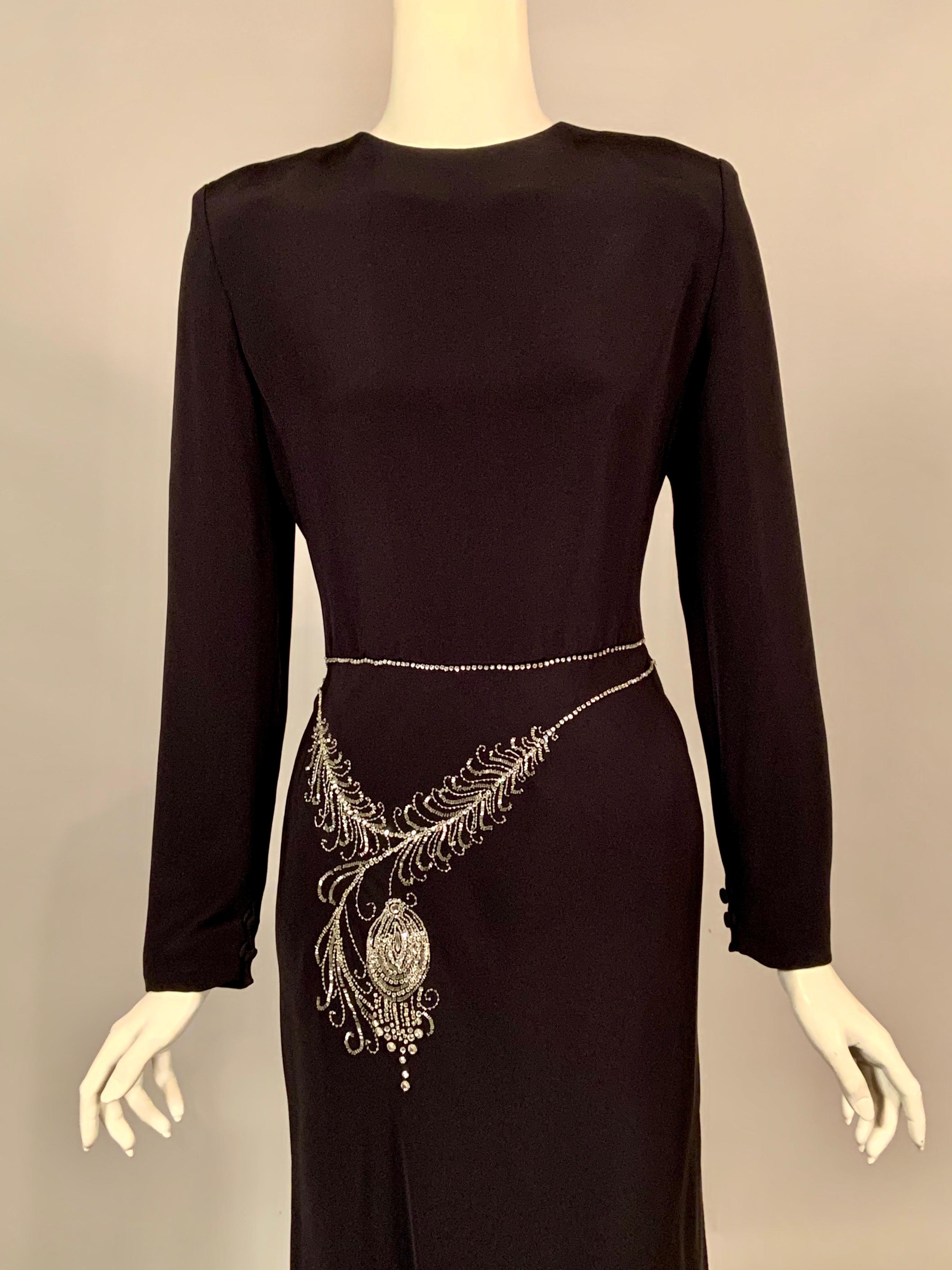 What a great design! This black silk evening dress from Bill Blass is a classic design with a fun twist. It has a round neckline, long sleeves with buttons and loops at the wrist, and a natural waistline. This is where the fun begins, the dress has