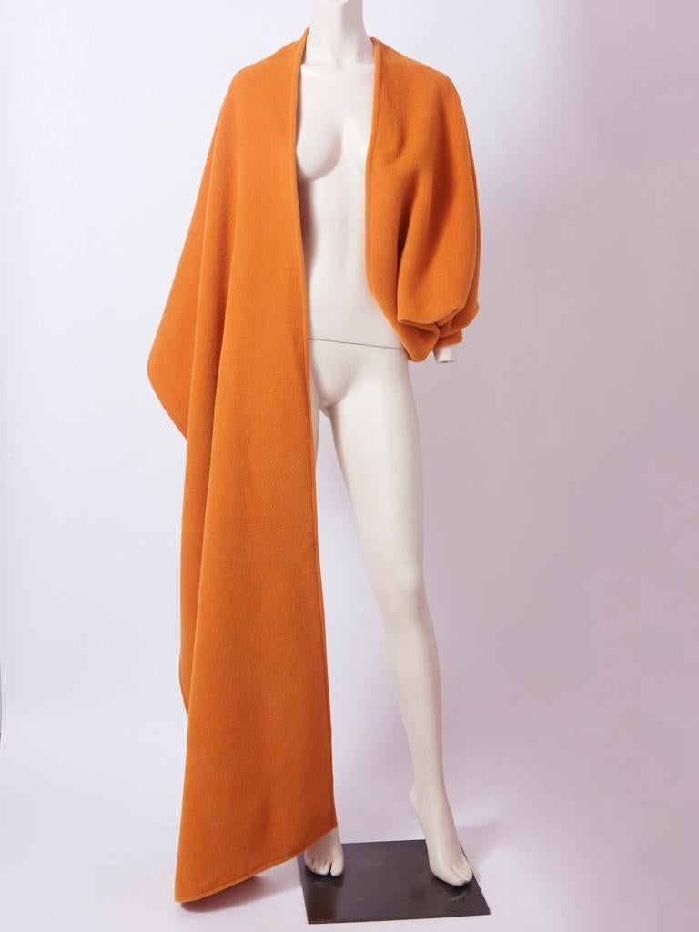 Bill Blass, pumpkin tone,  short, fleece wool, serape, having one sleeve and a shawl-like detail that extends and wraps around the shoulder.