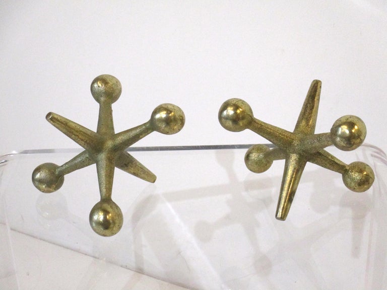A pair of large scaled cast solid brass Jacks typical for what children used back in the day. A nice accessory for home or office as bookends, paperweights or as sculpture designed by Bill Curry and manufactured by Design Line.