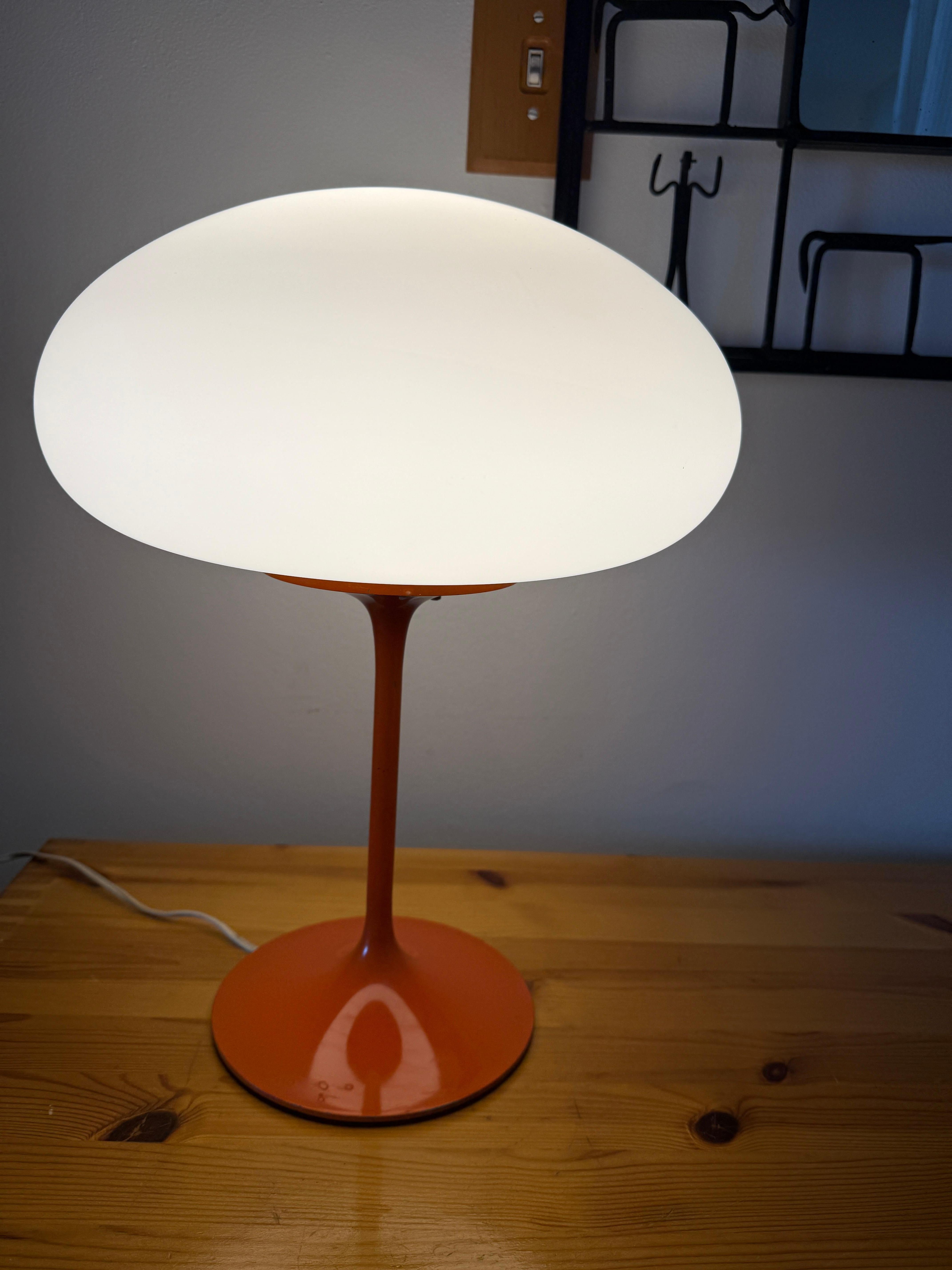 Original condition Bill Curry Stemlite Mushroom lamp featuring an enameled orange tulip base and frosted glass shade. The shade sets atop the base. The switch is a three-way switch and features varying Kelvins with each option. A beautiful addition