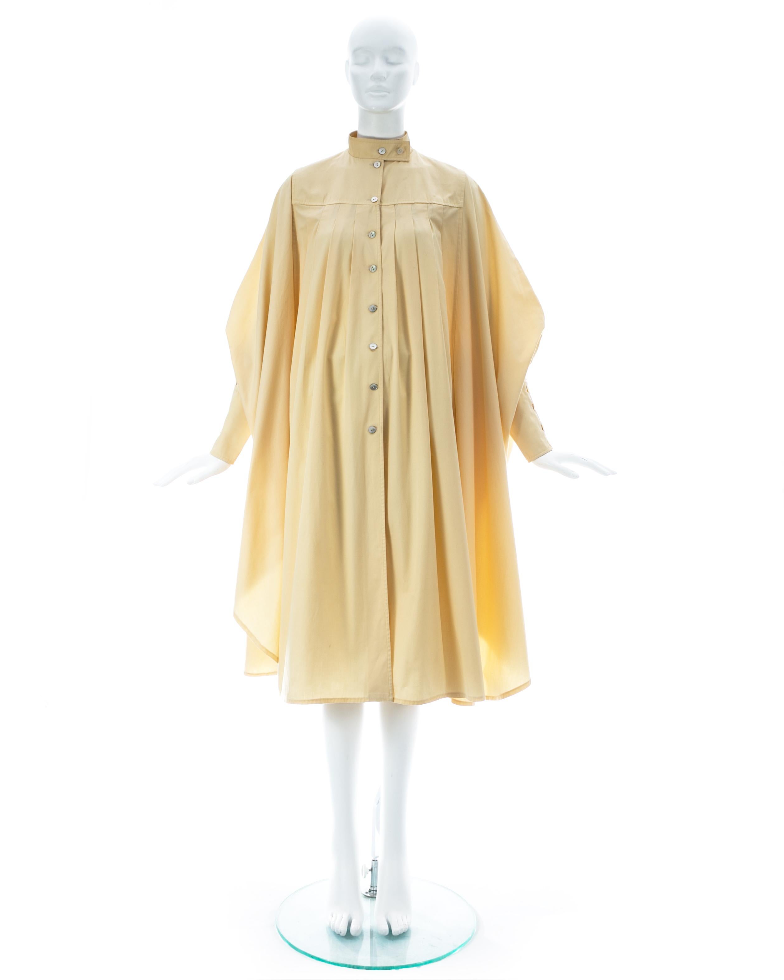 Cream cotton coat with box pleats, 2 side pockets, standing collar, and long fitted cuffs

ca. 1978