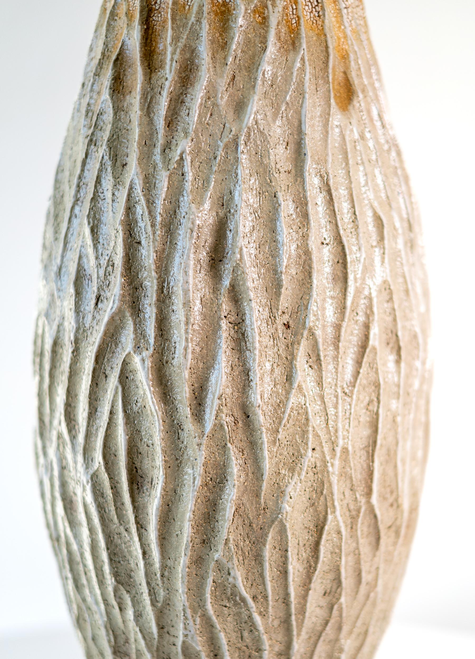 This unique tall ceramic vessel is handmade.

Bill Greaves creates handsome contemporary ceramics inspired by the colours, forms and textures found in nature. The Canadian ceramicist hand coils his eclectic vessels to build the form. The remarkable