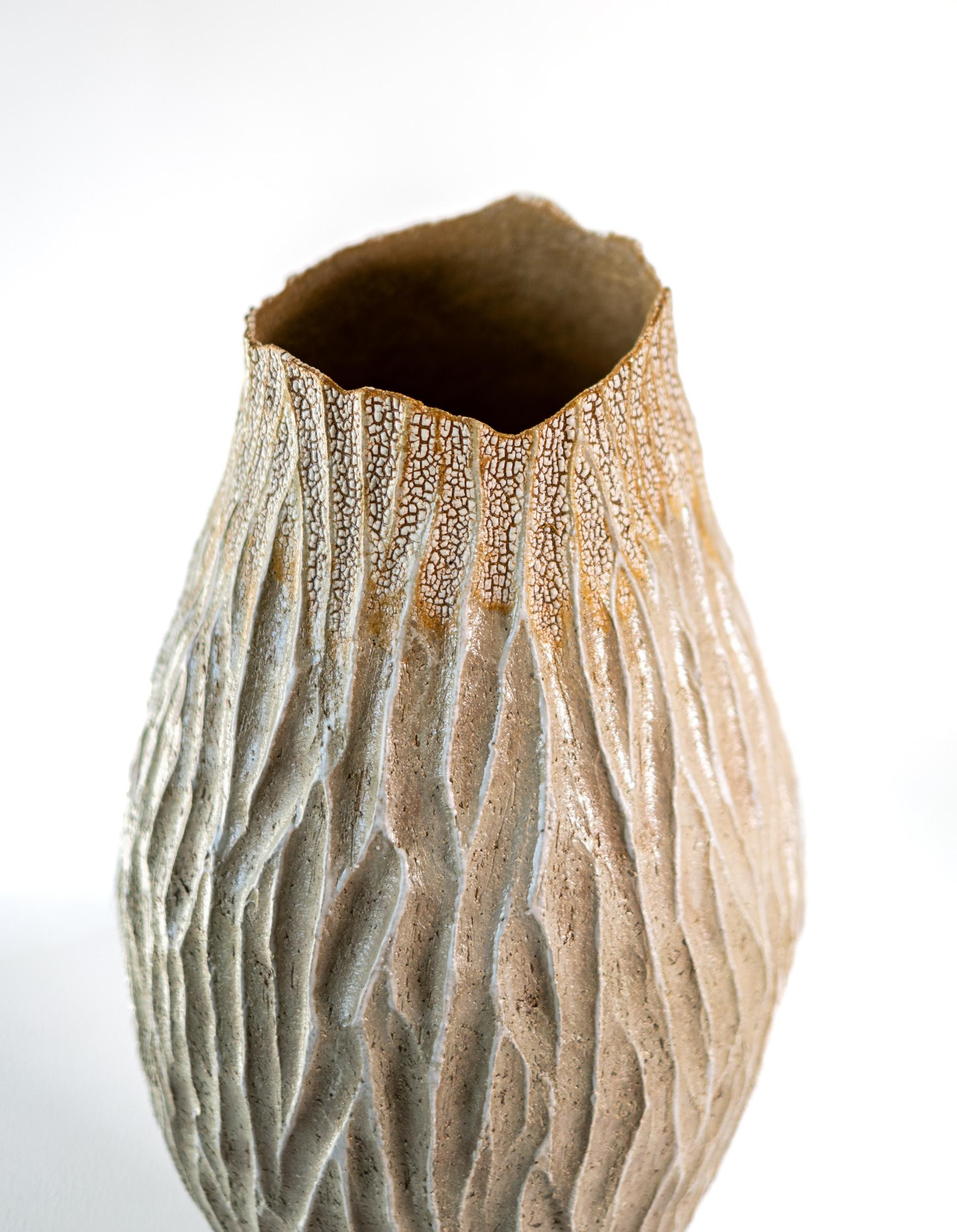 This unique tall ceramic vessel is handmade.

Bill Greaves creates handsome contemporary ceramics inspired by the colours, forms and textures found in nature. The Canadian ceramicist hand coils his eclectic vessels, building the forms. The