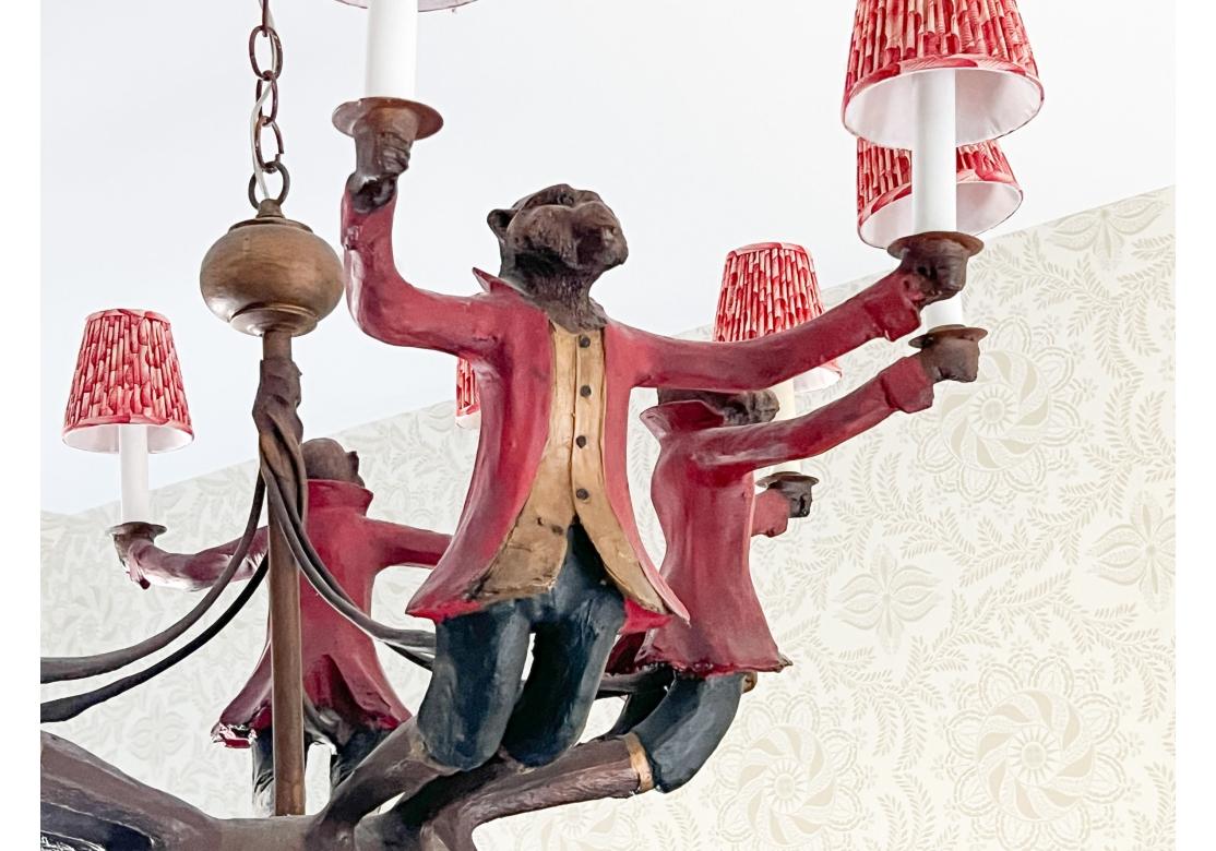 By Huebbe Designs, the wondrous resin and mixed media chandelier is in the form of five monkeys wearing red coats, each holding two candle sockets with shades.

Dimensions: 37” diameter by 22.5” high. 

Condition: Please see detail photos. Various