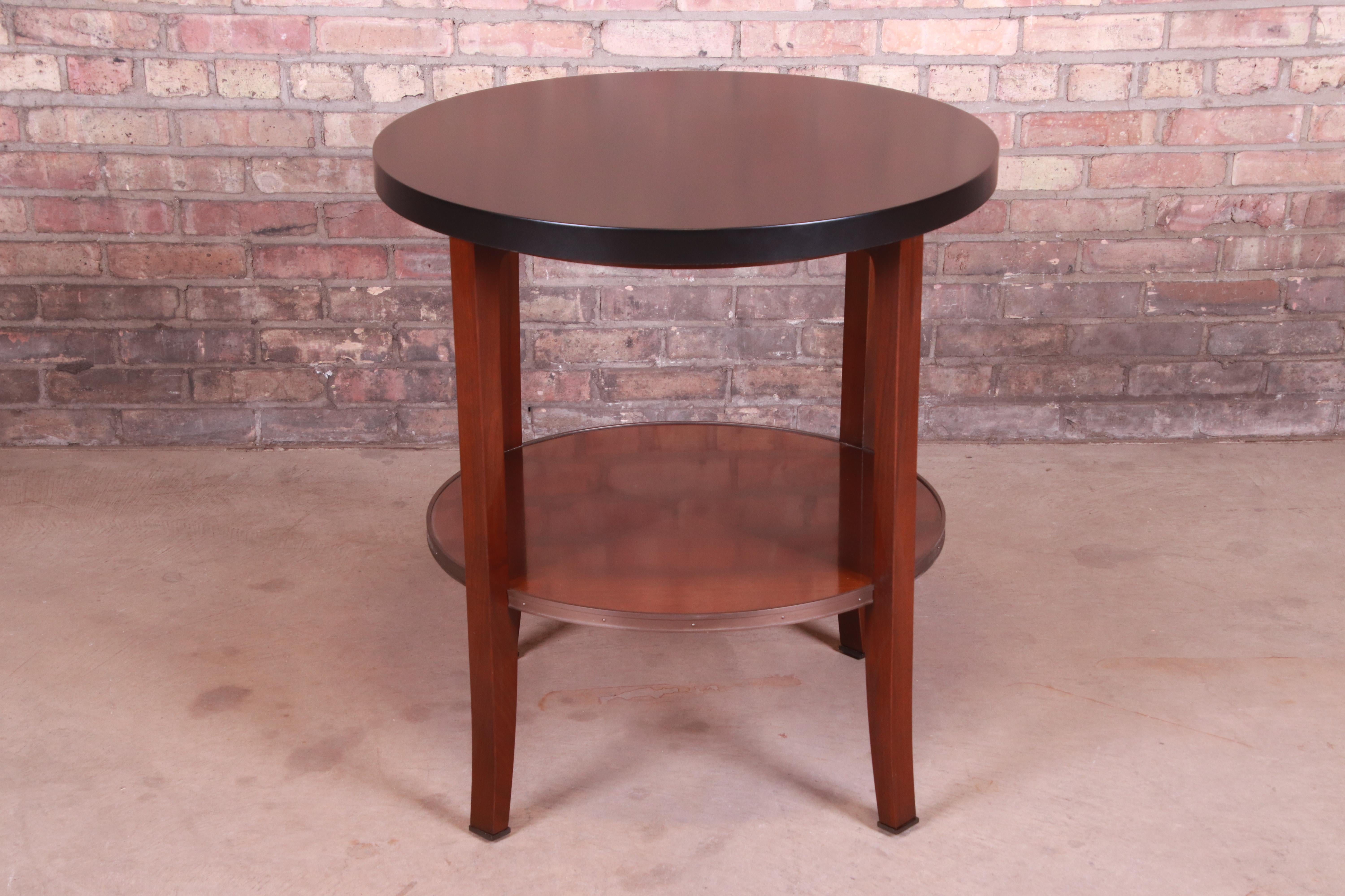 A gorgeous two-tier tea table or occasional side table

By Bill Sofield for Baker Furniture

USA, early 21st century

Mahogany, with black lacquered top and brass accents.

Measures: 28