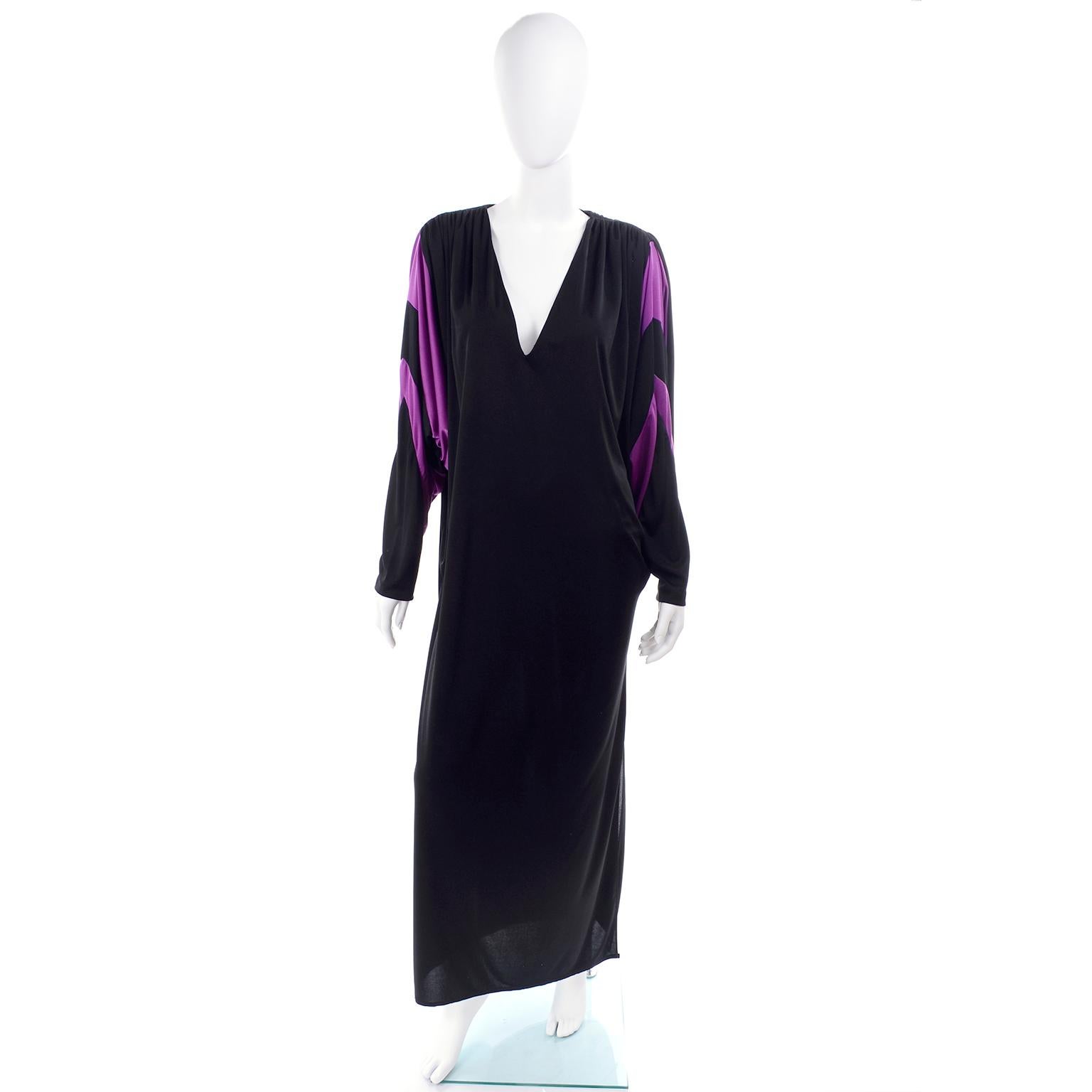 This is a great vintage dress designed by Bill Tice in the late 1970's This full length dress is black with dramatic purple stripes on the exaggerated leg of mutton batwing sleeves. The dress is in a jersey fabric that is draped on the side with a