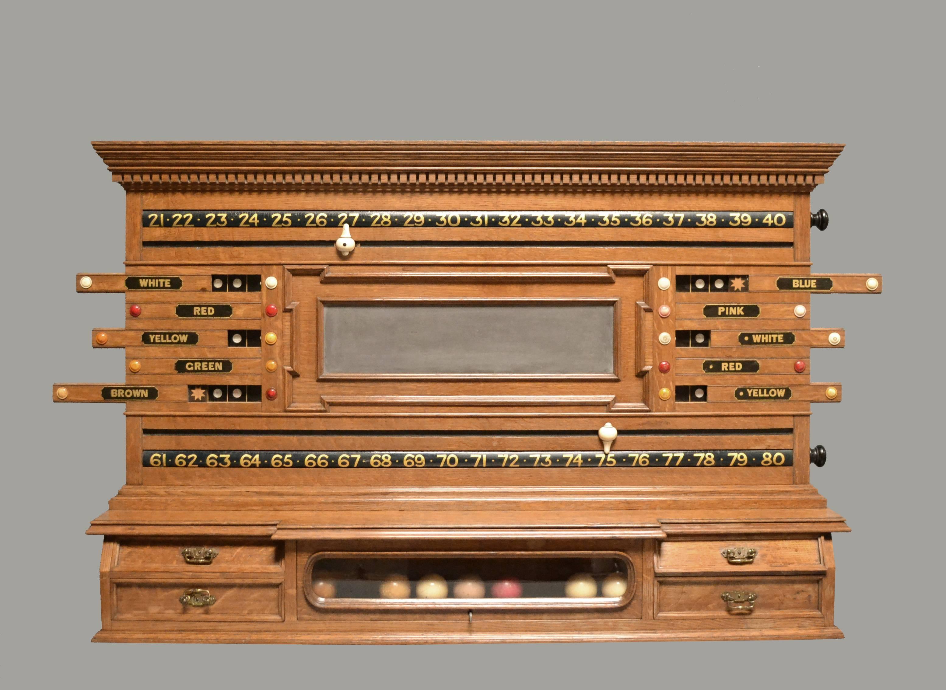This golden oak wall-mounted scoring cabinet with a decorative dentil frieze was probably made by Burroughes & Watts of London, circa 1890, it features two revolving ratchets and a central panelled slate section which is flanked by Life pool