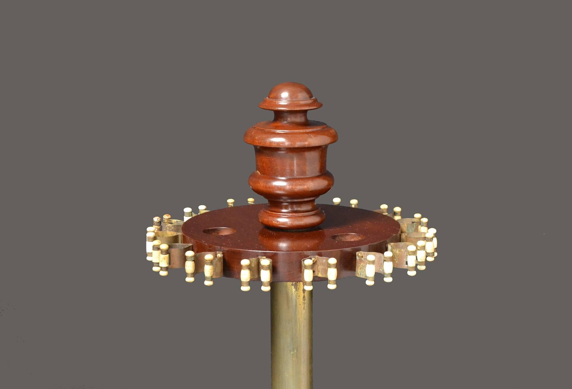 A very good quality mahogany billiard cue stand probably by Thurston of London manufactured, circa 1860.

A central brass upright column supports a circular top with a decorative finial and brass sprung cue clips which hold up to 15 cues, all