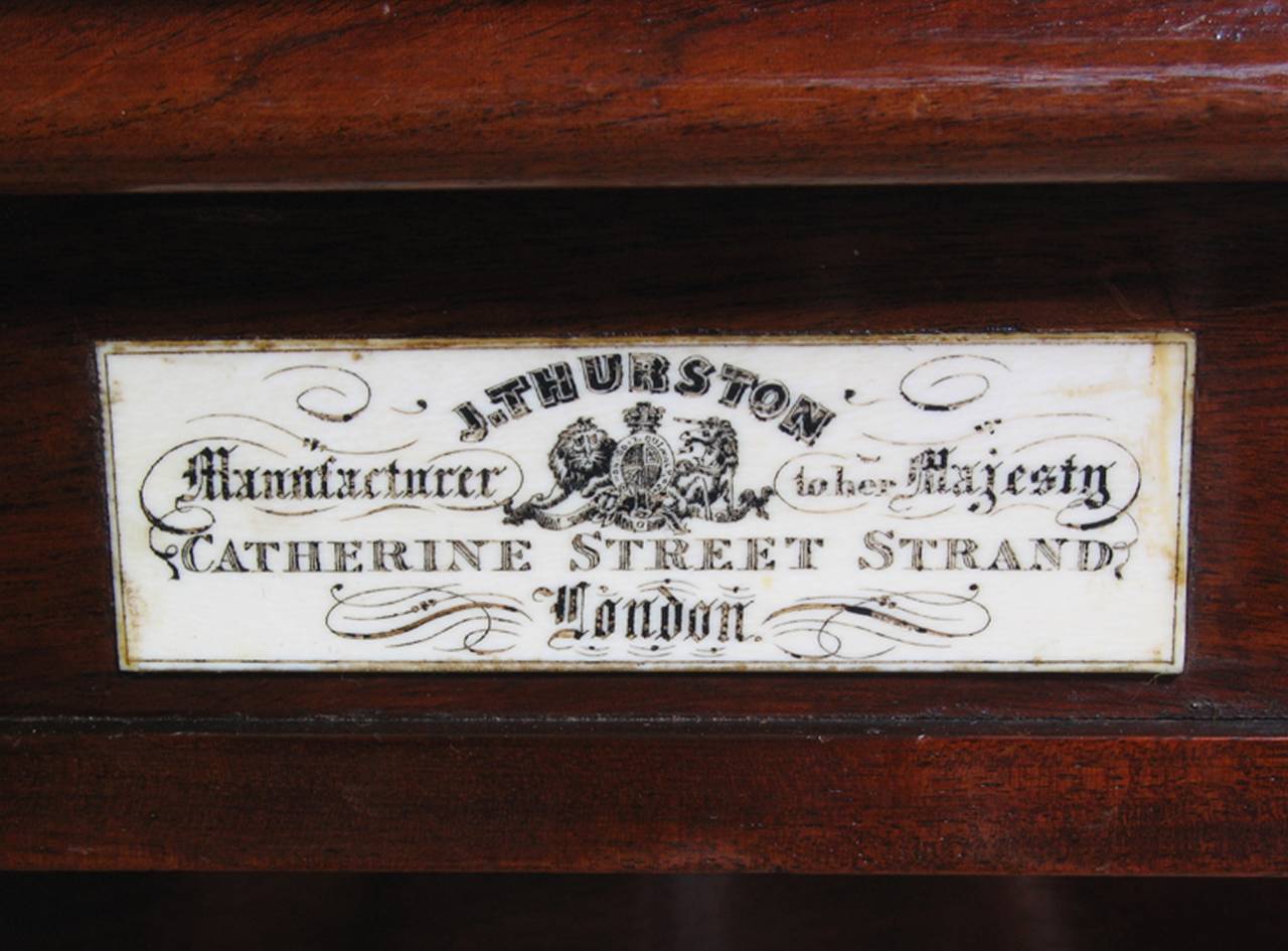 A mahogany antique billiard or snooker table by John Thurston of London, circa 1850, standing on eight elegant turned legs with applied bosses to the blocks and cushions, comprising an original slate bed and beautifully fitted brass pocket