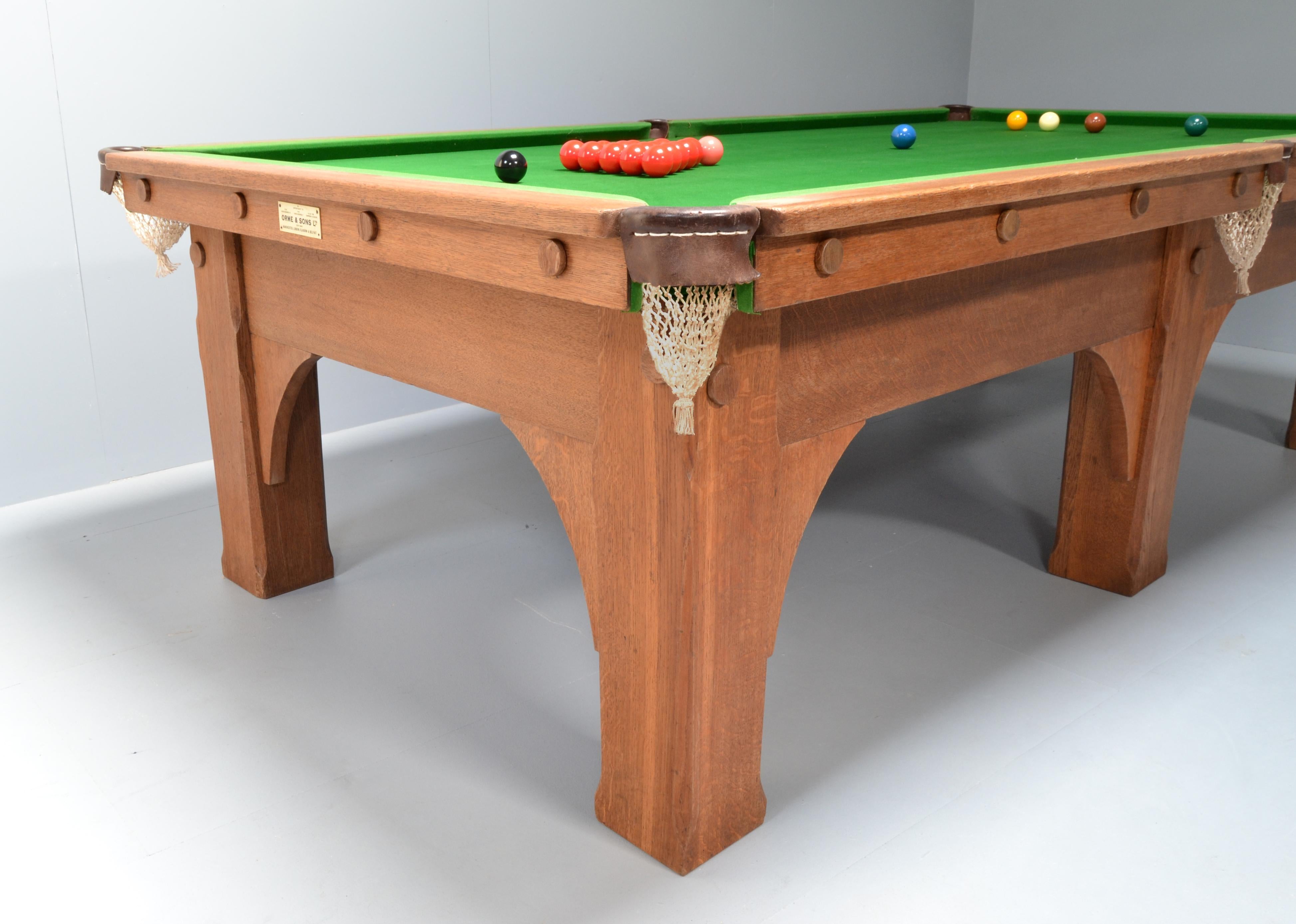 An English Arts & Crafts solid oak billiard, snooker or pool table made by Orme & Sons, circa 1910.

Standing on six square chamfered legs with substantial arched brackets, the legs and cushion edges are fitted with applied bosses.

All