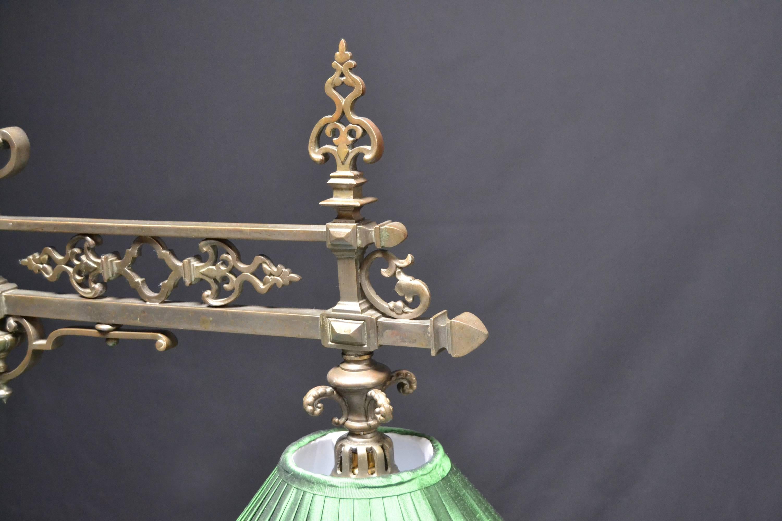 A superb decorative cast brass framed Billiard , snooker or pool table lamp featuring a central horizontal framed frieze with ornamental castings , joined to a central upright via embellished cast braces, adorned with a cast symbol of 