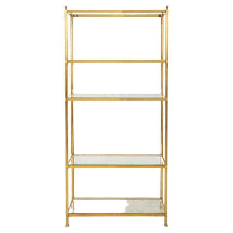 A four-shelf étagère exquisitely crafted in the iconic style of Billy Baldwin. This stunning piece seamlessly marries the opulence of brass with the airy allure of glass, creating a harmonious blend of glamour and functionality that transcends the