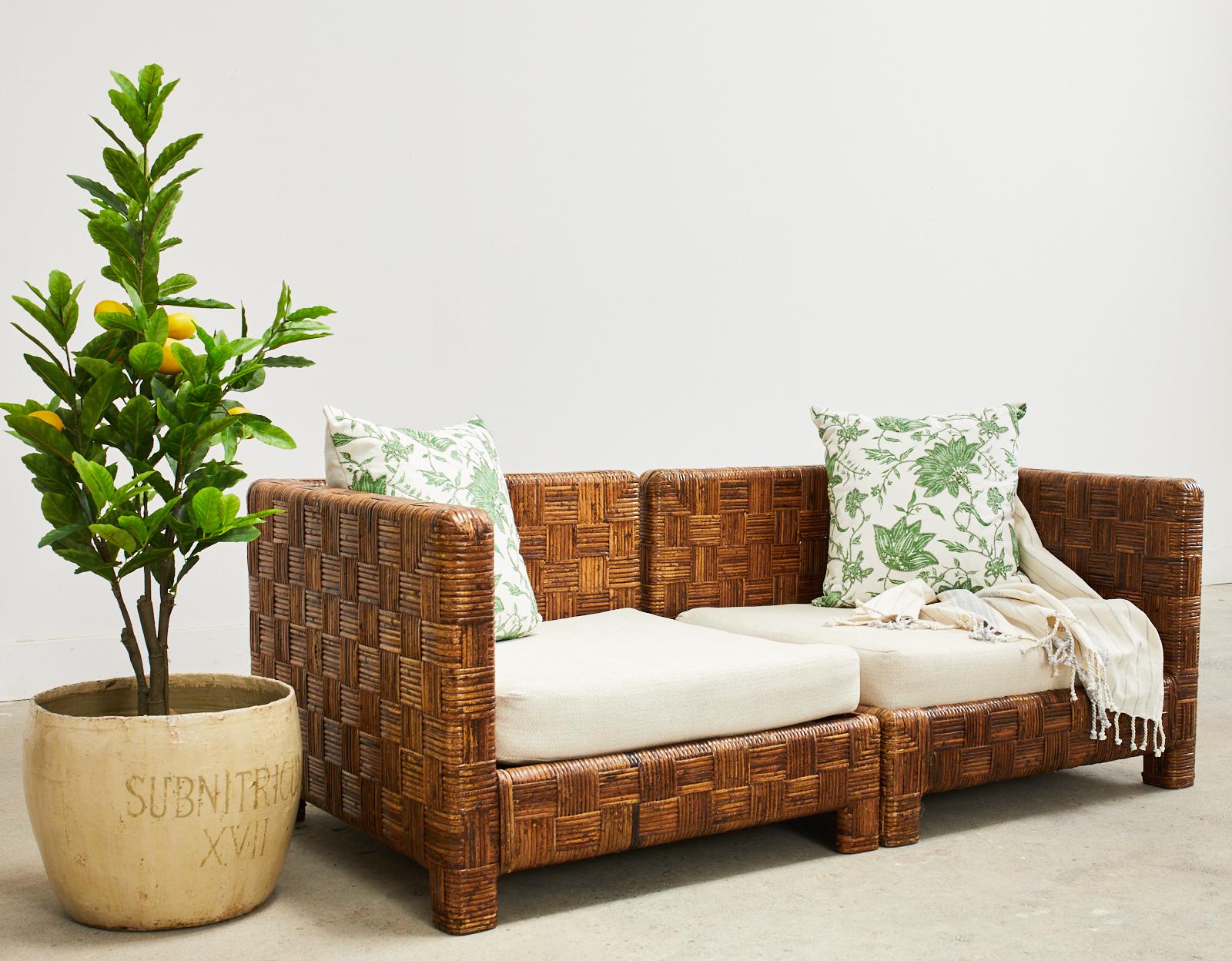 Stylish cane basketweave two-part parsons sofa or settee made in the style and manner of Billy Baldwin. Beautifully crafted from a wood frame embellished in a geometric pattern cane basketweave. Each cube shaped section measures 32 inches wide and