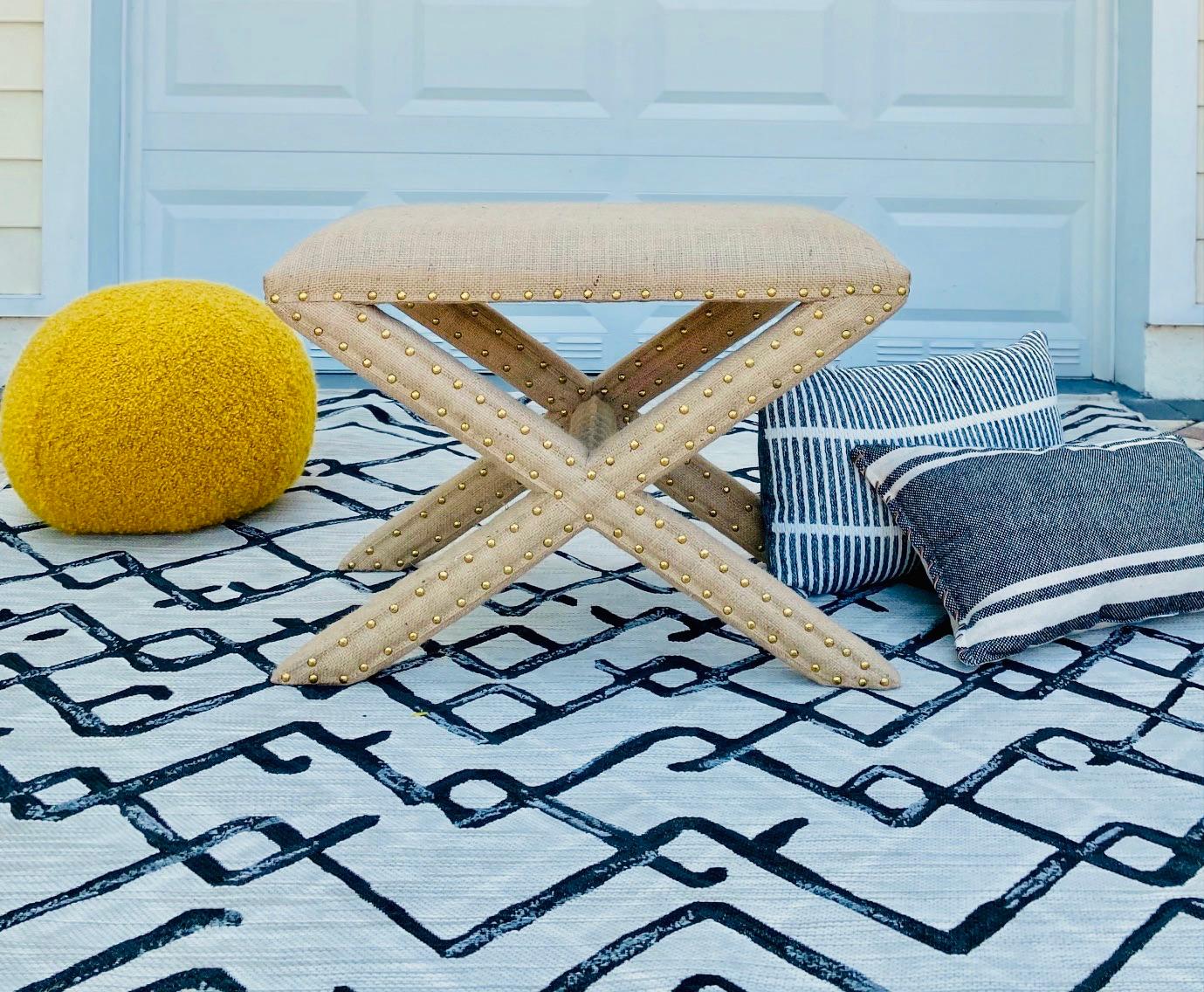 Hollywood Regency style bench with stylized X Base frame in the style of Billy Baldwin. Completely upholstered in organic jute fiber burlap fabric with gold nail studs throughout. Makes a chic accent bench for any room.