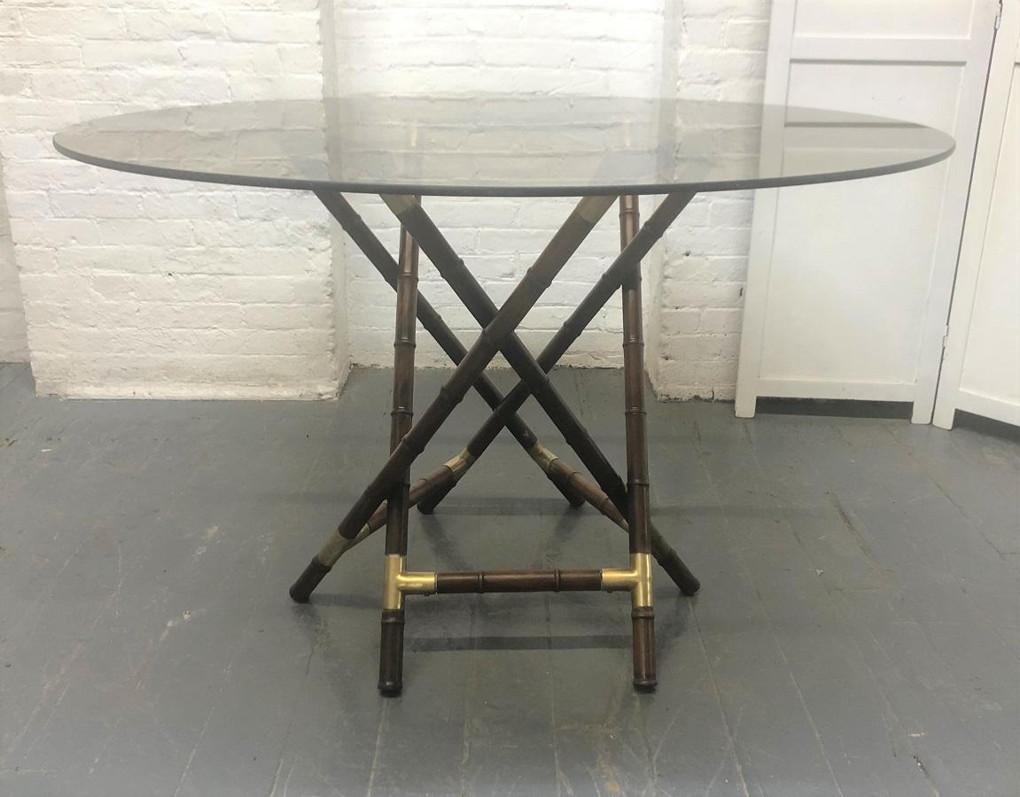 Billy Haines style faux bamboo and bronze dining set. The table and chairs have faux bamboo wood frames with bronze mounts. The table has a smoked glass top. There are four chairs with this dining set.
Table measures: 47.25 in diameter x 29.5
