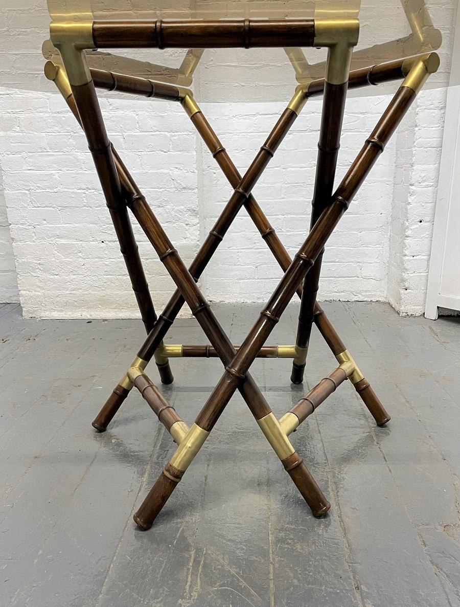 Billy Haines faux bamboo glass top table. The table has a faux bamboo wood frame with bronze mounts. Table has a round smoked glass top.