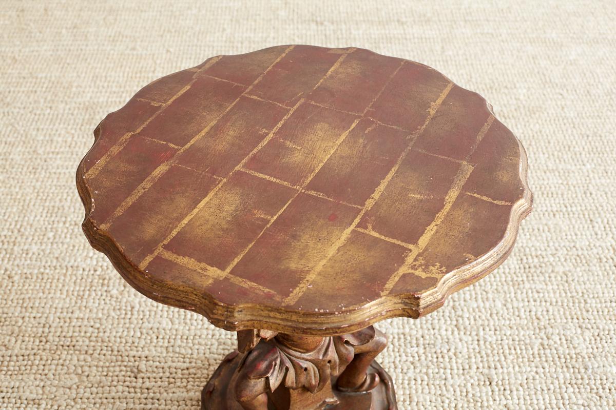 Sculptural Italian drinks table made in the chinoiserie taste. Features a Billy Haines style seated Chinese man supporting the top. Finished with squares of gilt over a lacquered base that give it a rich, vintage patina. The top has a scalloped