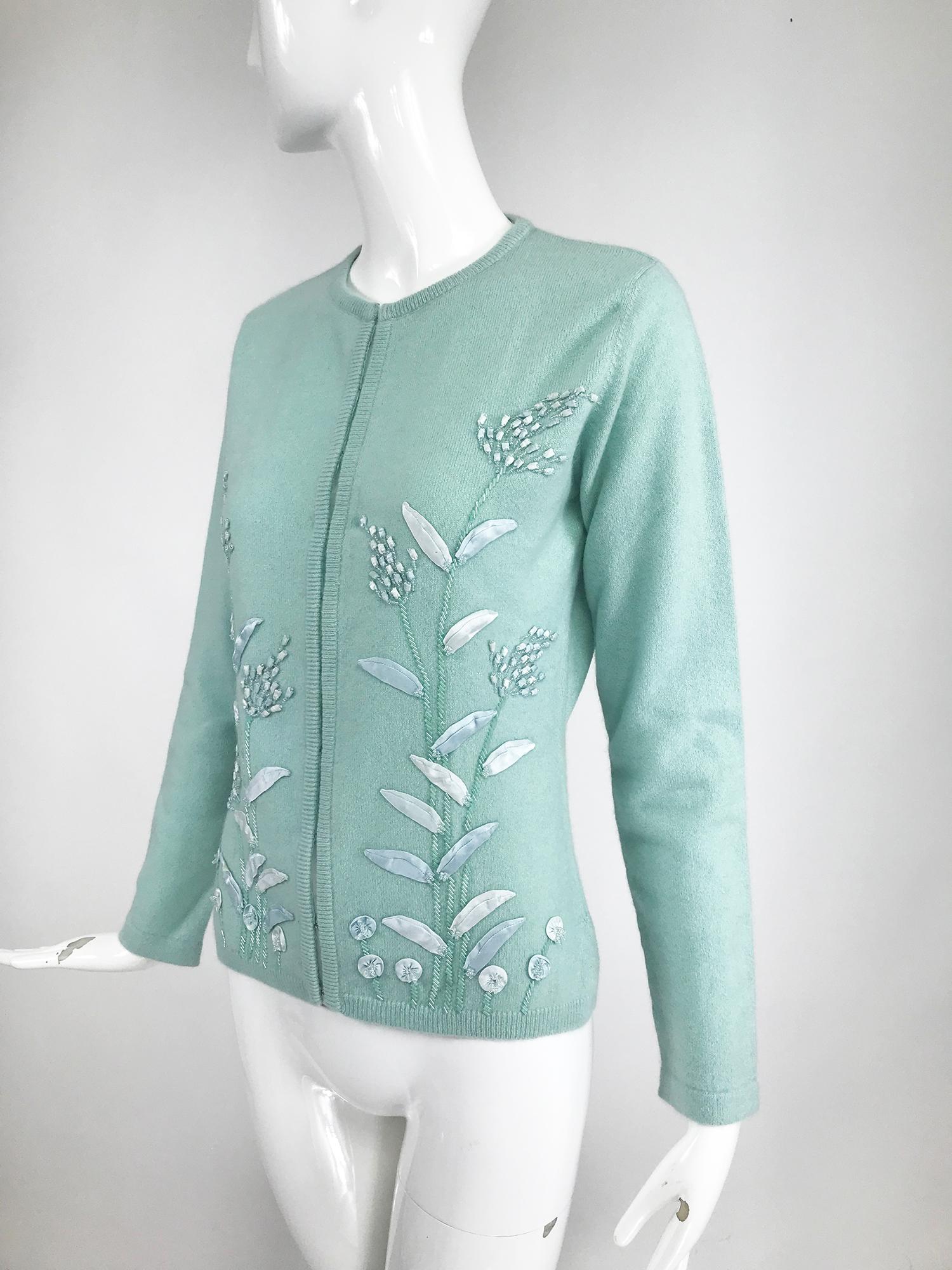 Lara Bilzerian hand appliqued robin's egg blue cashmere cardigan sweater. This beautiful sweater has beaded and satin ribbon appliqued flower motifs on each front side. The long sleeve sweater closes at the front with hidden hook and eyes. Ribbed