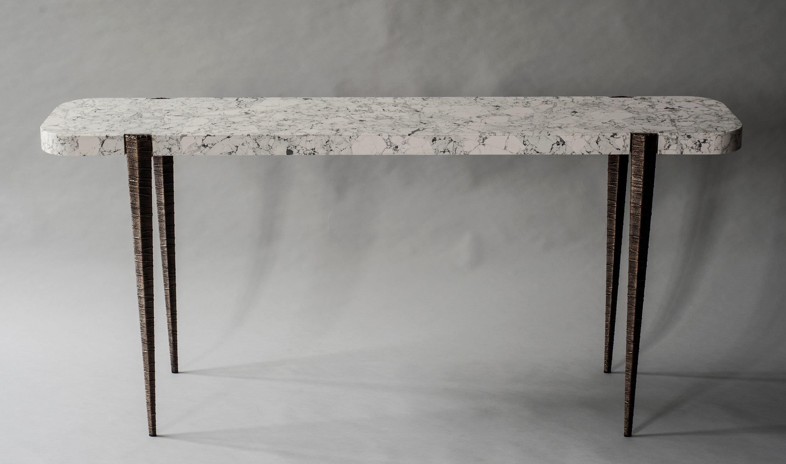 The bind console by DeMuro Das features a striking stone top in Howlite, with crisp white undertones and spidery charcoal veining. The top is supported by elegantly tapered and textured hand-cast legs in solid antique bronze.