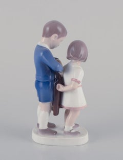 Bing and Grondahl, porcelain figurine. Boy helping girl with her jacket.