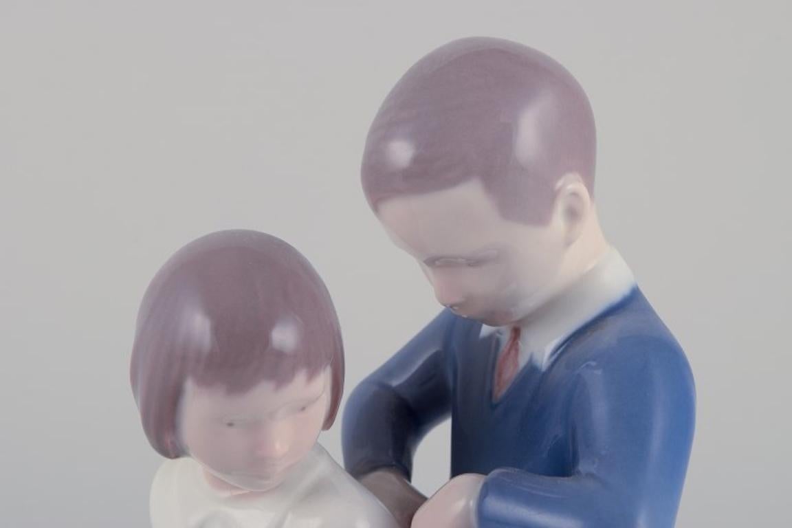 Bing e Grondahl, statuetta in porcellana. Ragazzo che aiuta la ragazza con la sua giacca. In condizioni ottime in vendita a Copenhagen, DK