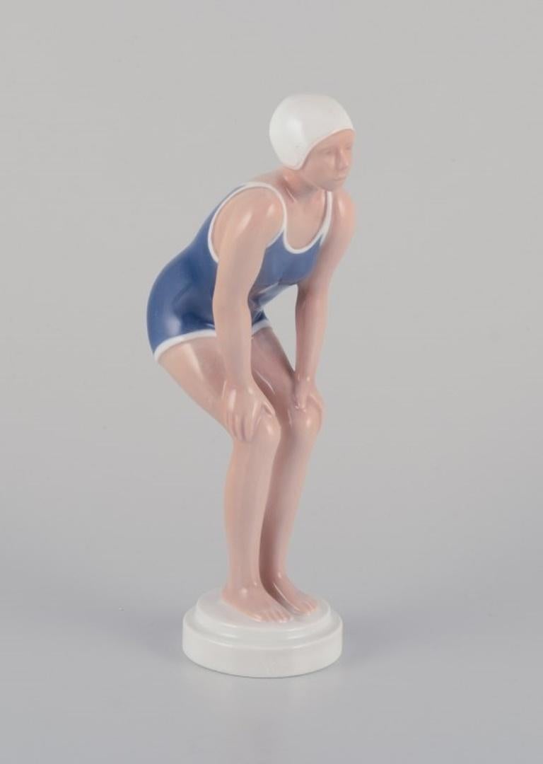 Bing y Grondahl, figurita de porcelana de niña en bañador. 
Rara figura Art Decó.
Model No. 2224
Ca. 1930s.
Primera calidad de fábrica.
En perfecto estado.
Dimensiones: Alto 20,2 cm. x Ancho 8,0 cm.
