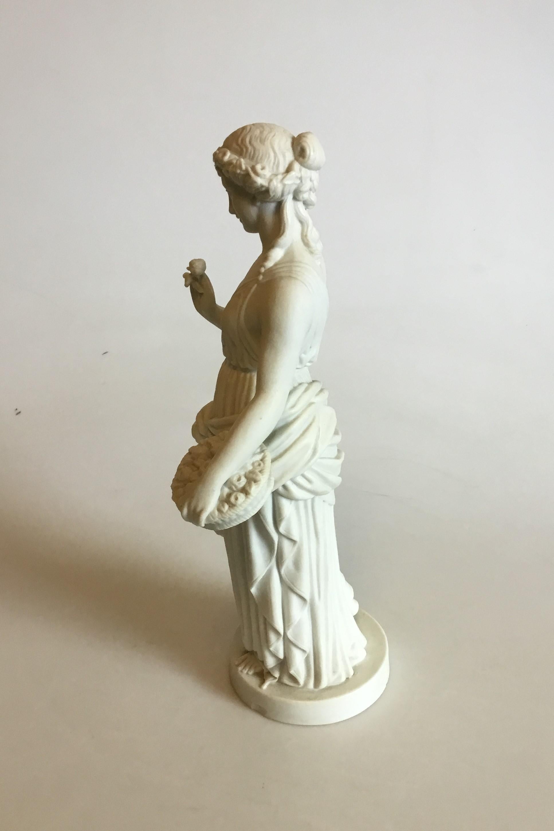 Bing & Grøndahl biscuit figurine of standing woman with flower basket. Measures: 31 cm / 12 13/64 in. Chip on base.