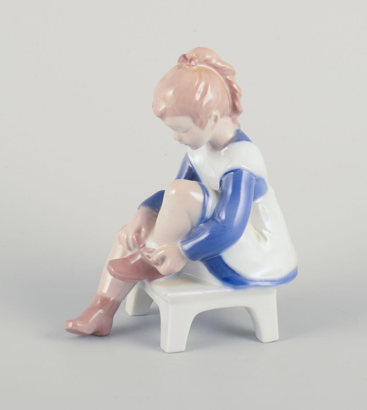 Pre-owned goods are exempt from import duties for U.S. customers. 
Therefore, no import tariffs will be applicable to your purchase.

Bing & Grøndahl porcelain figurine, sitting girl tying a shoelace.
Underglaze.
1970s
Model: 2373
Marked.
First