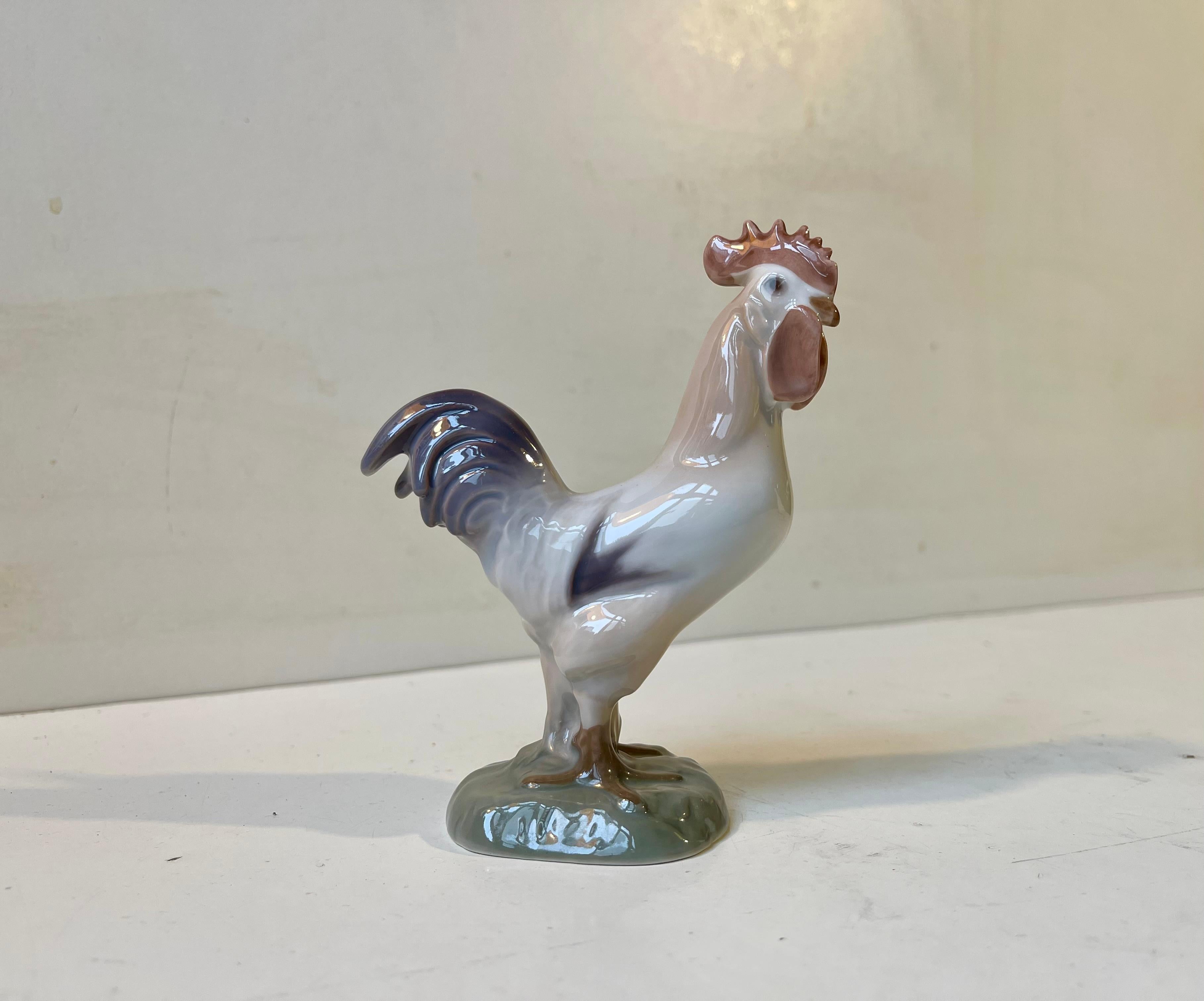 Naturalistically glazed rooster in porcelain by Bing & Grondahl in Denmark. Based upon a antique dessin this particular example was made circa 1970. Decoration number 2192. The condition is wellkept, clean and intact. Measurements: 12/9 cm.