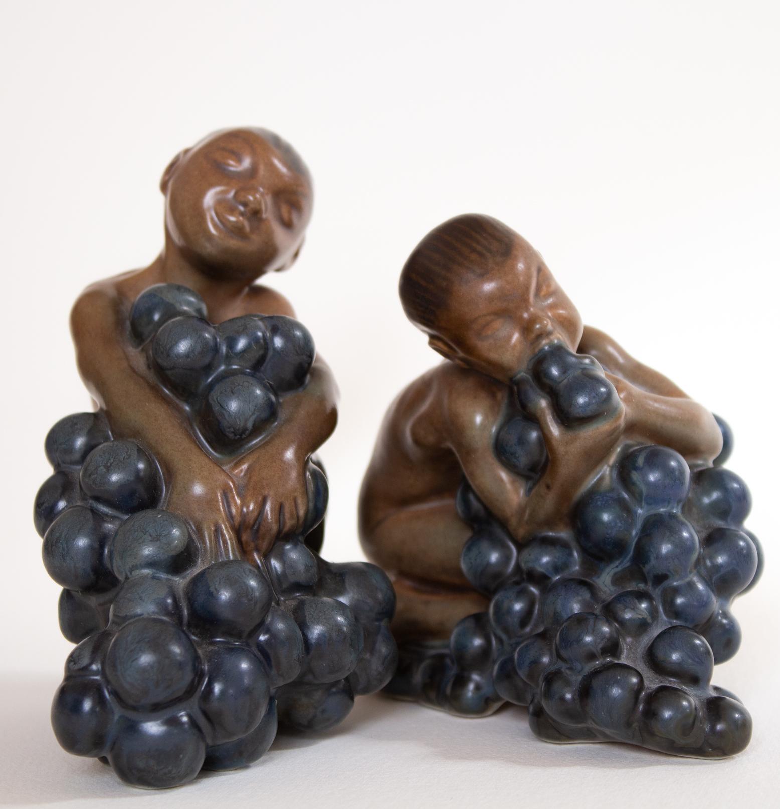 Bacchus and a boy with grapes by Kai Nielsen (1882–1924). From Bing and Gröndahl. Signed on the base. Boy: Number 21. (1912) 11 x 10 cm. And A 51. (t279) 13 x 13 cm. The figurines is from the series 'Grape Harvesting.' 
Suited as a nice gift for