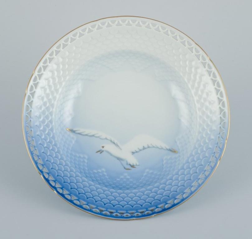Bing & Grøndahl, three deep plates with reticulated rim and gold decoration. 
Motif of seagull.
1970s.
Model 323.5
In perfect condition.
First factory quality.
Stamped.
Dimensions: D 21.5 x H 4.0 cm.