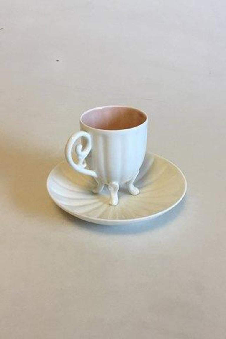 Bing & Grondahl Art Nouveau Mocha cup with saucer. Cup on four legs and inside with pink glaze. 

Measures cup: 7 cm / 2 3/4 in. x 5.5 cm / 2 11/64 in. diameter Saucer: 12 cm / 4 23/32 in.
   